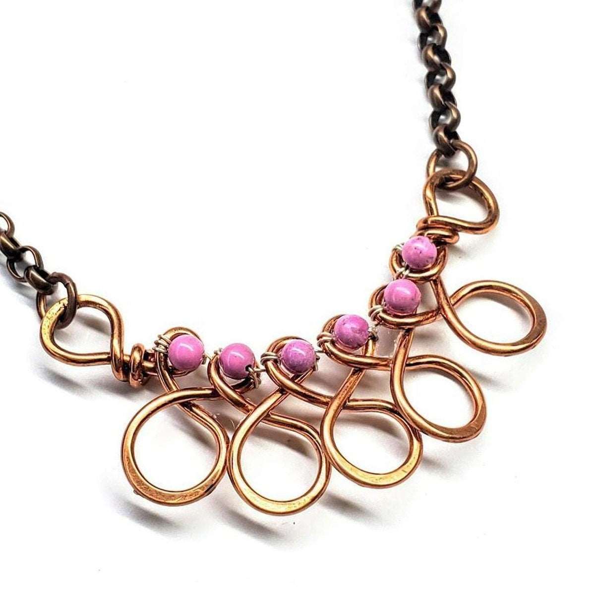 A luxurious copper wire wrapped necklace featuring a sculpted middle piece and purple magnesite beads, elegantly displayed on a model.