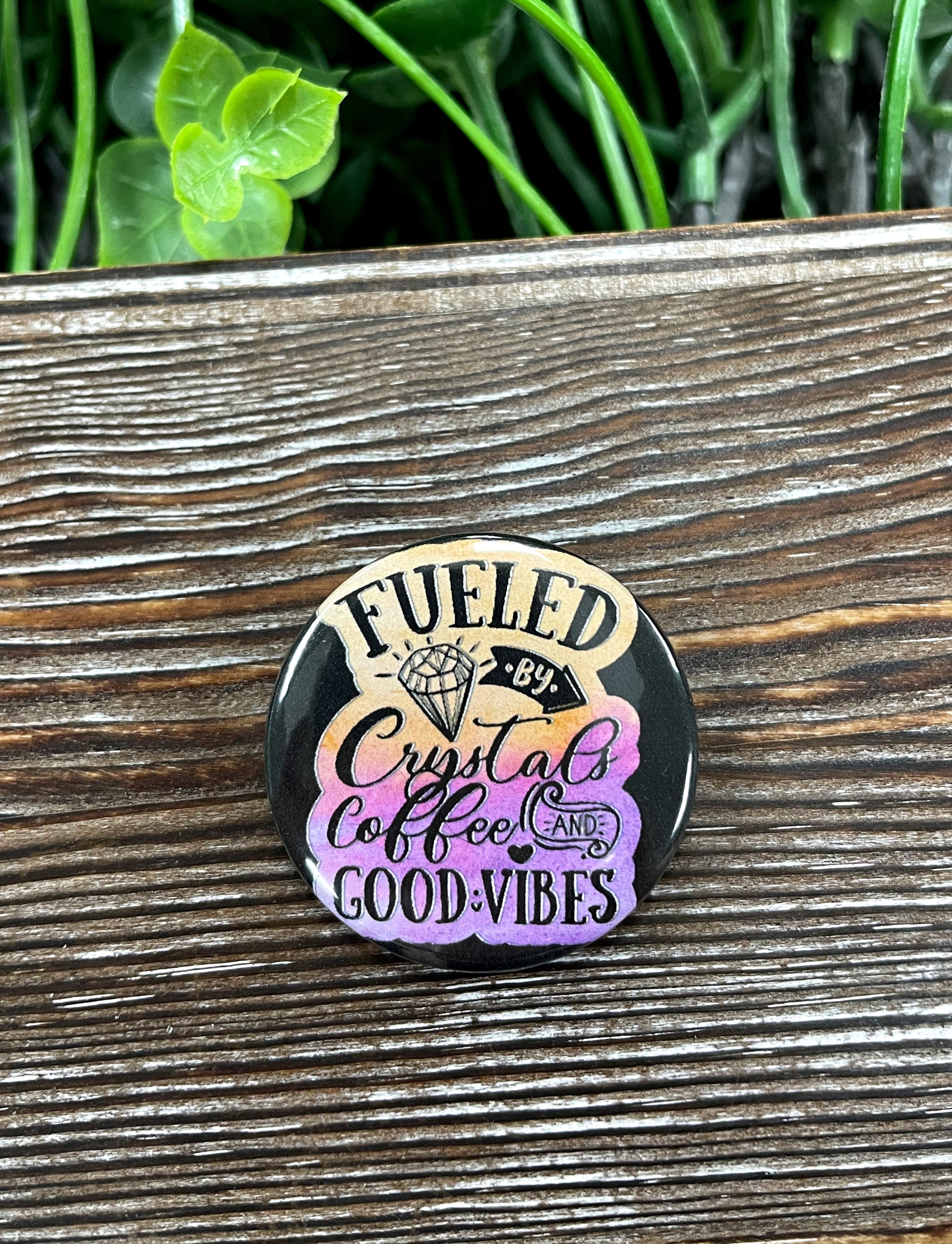 A colorful 1.25-inch button featuring a graphic design of crystals and coffee, perfect for personal expression.