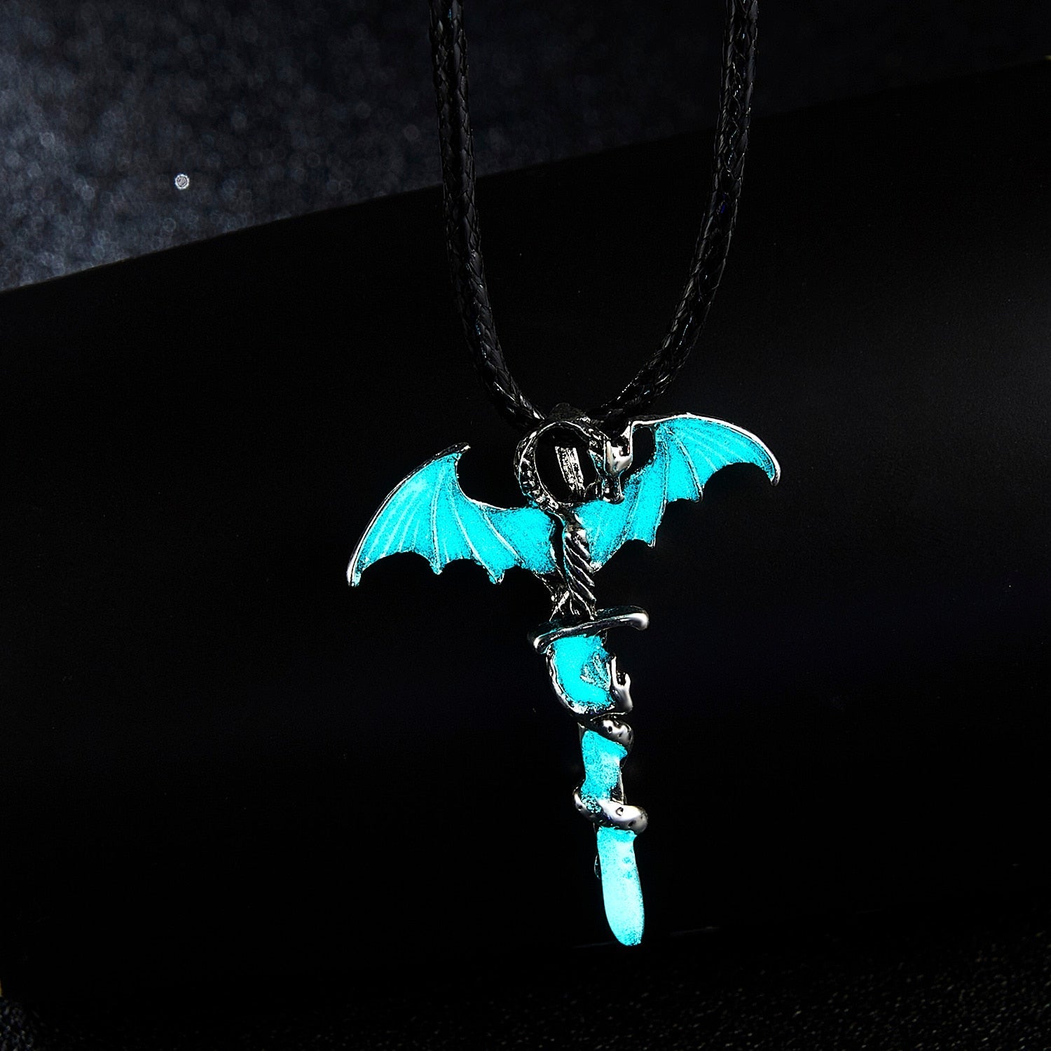 A glowing dragon pendant on a rope necklace, showcasing intricate details in blue, blue-green, and yellow-green colors.