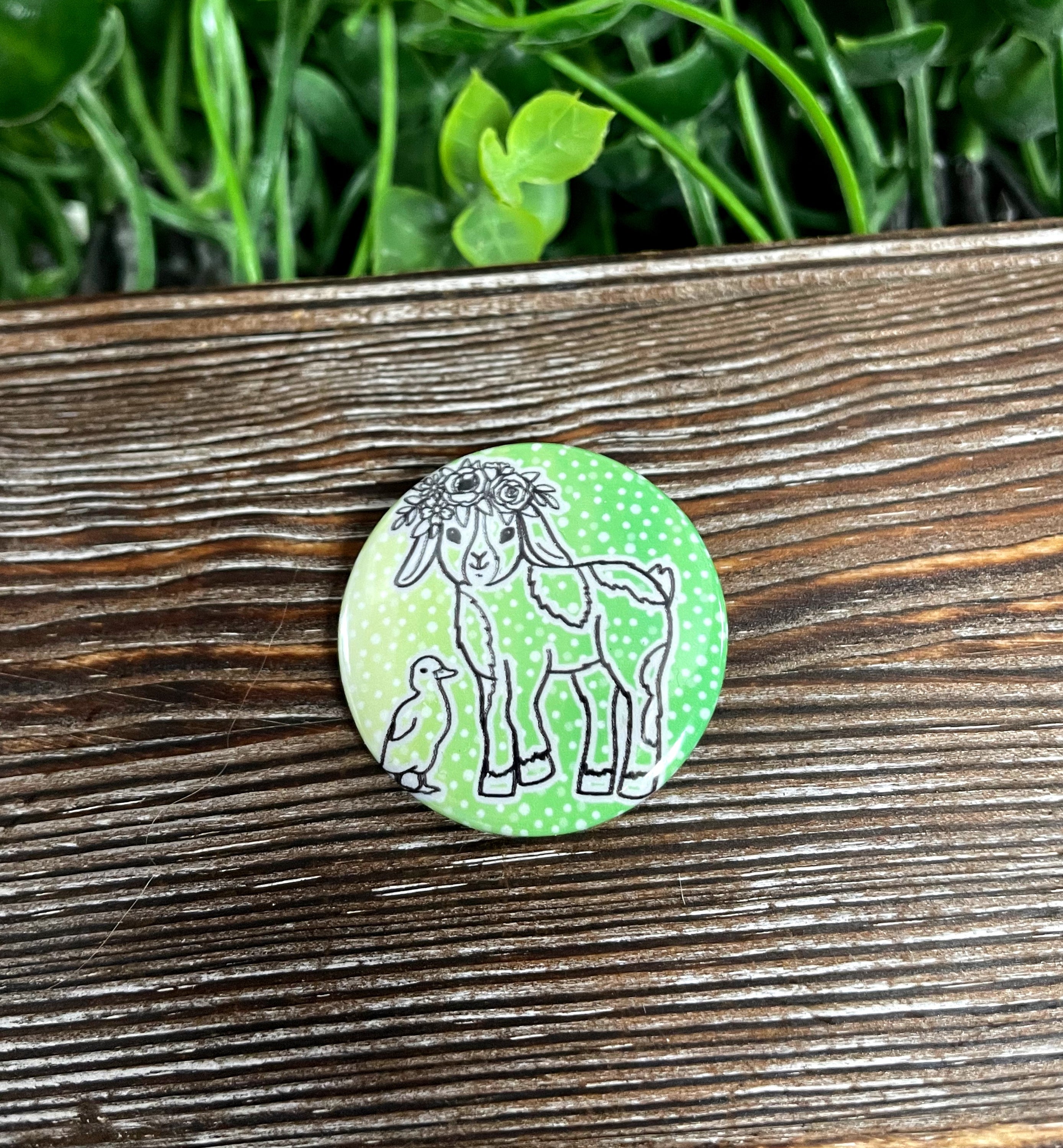 A colorful graphic art button featuring a goat with a flower crown and a duck, measuring 1.25 inches, perfect for personalizing bags and accessories.