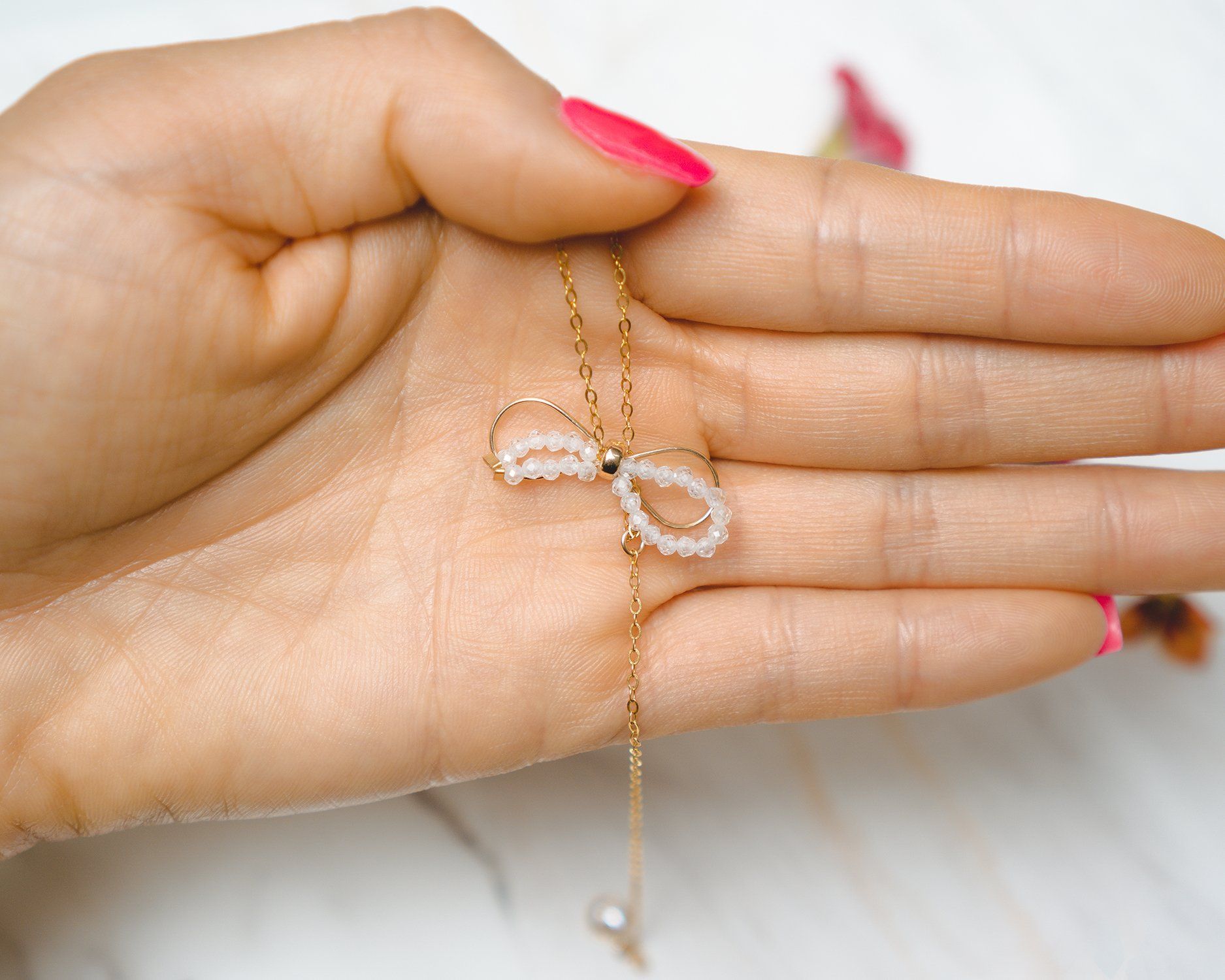 A delicate Handmade Dainty Bow Necklace featuring a crystal bow pendant and cubic zirconia accents, crafted from 14k gold filled material.