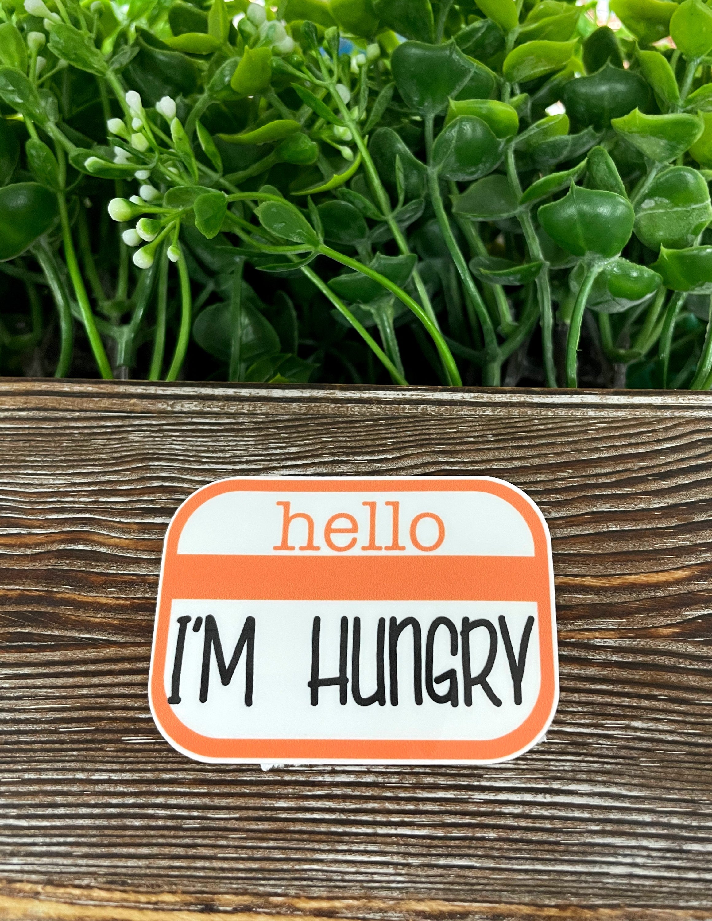 Hello I'm Hungry Badge die cut vinyl sticker on a smooth surface, showcasing vibrant colors and fun design.