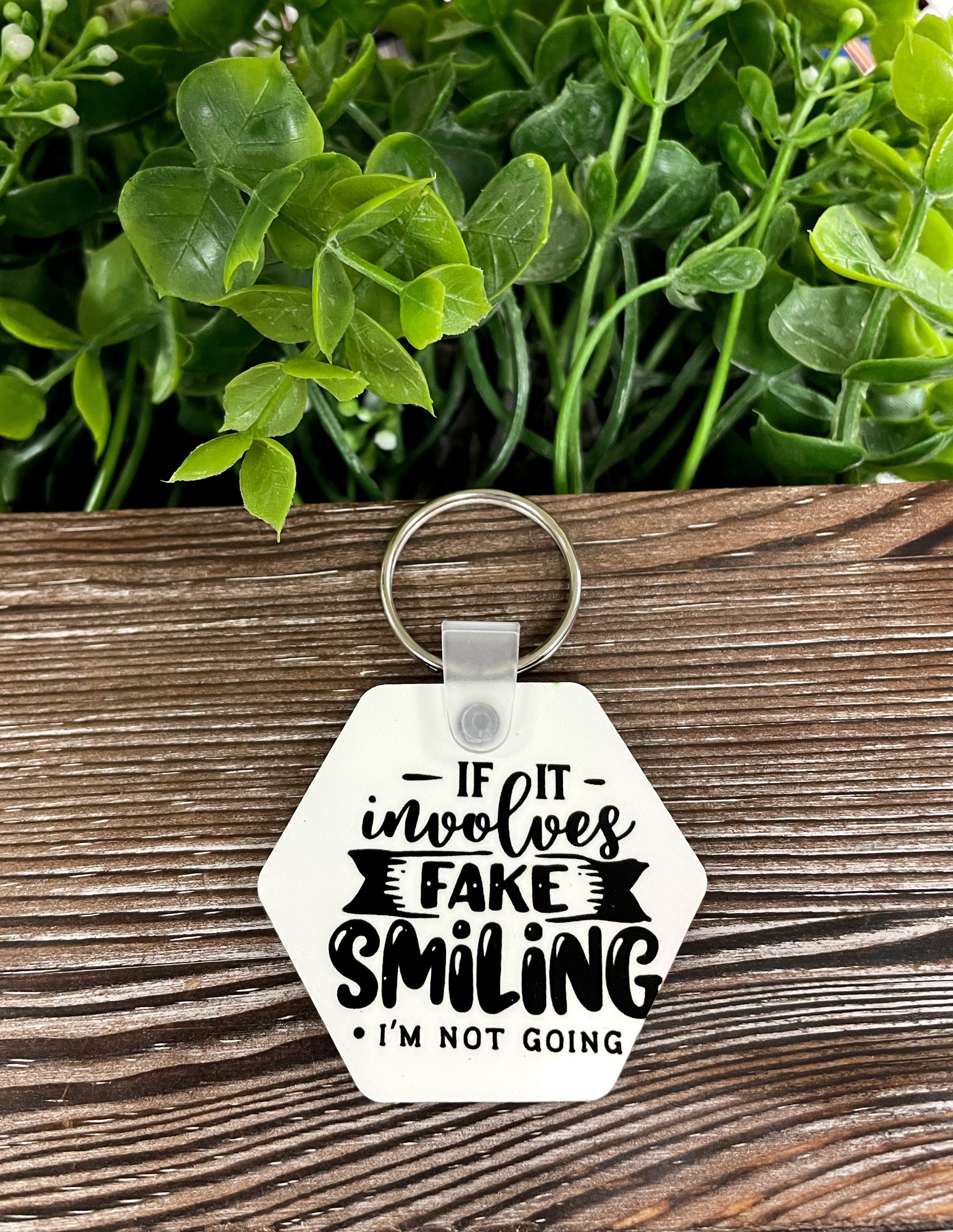 MDF hexagon keychain with the quote 'If it Involves Fake Smiling I'm Not Going', showcasing its lightweight and stylish design.