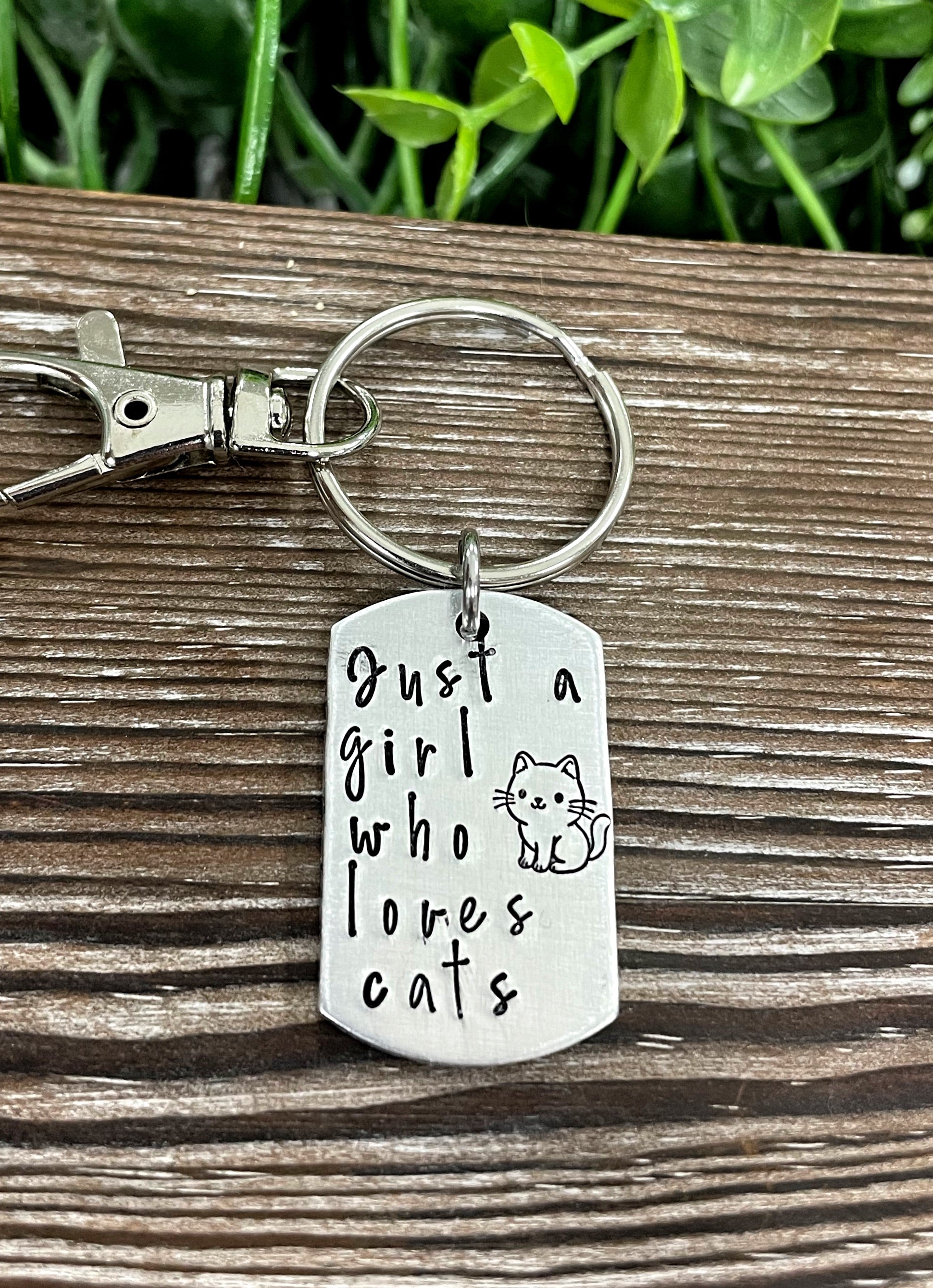 Hand-stamped key chain featuring the phrase 'Just a Girl Who Loves Cats', showcasing unique letter variations and a fun animal theme.