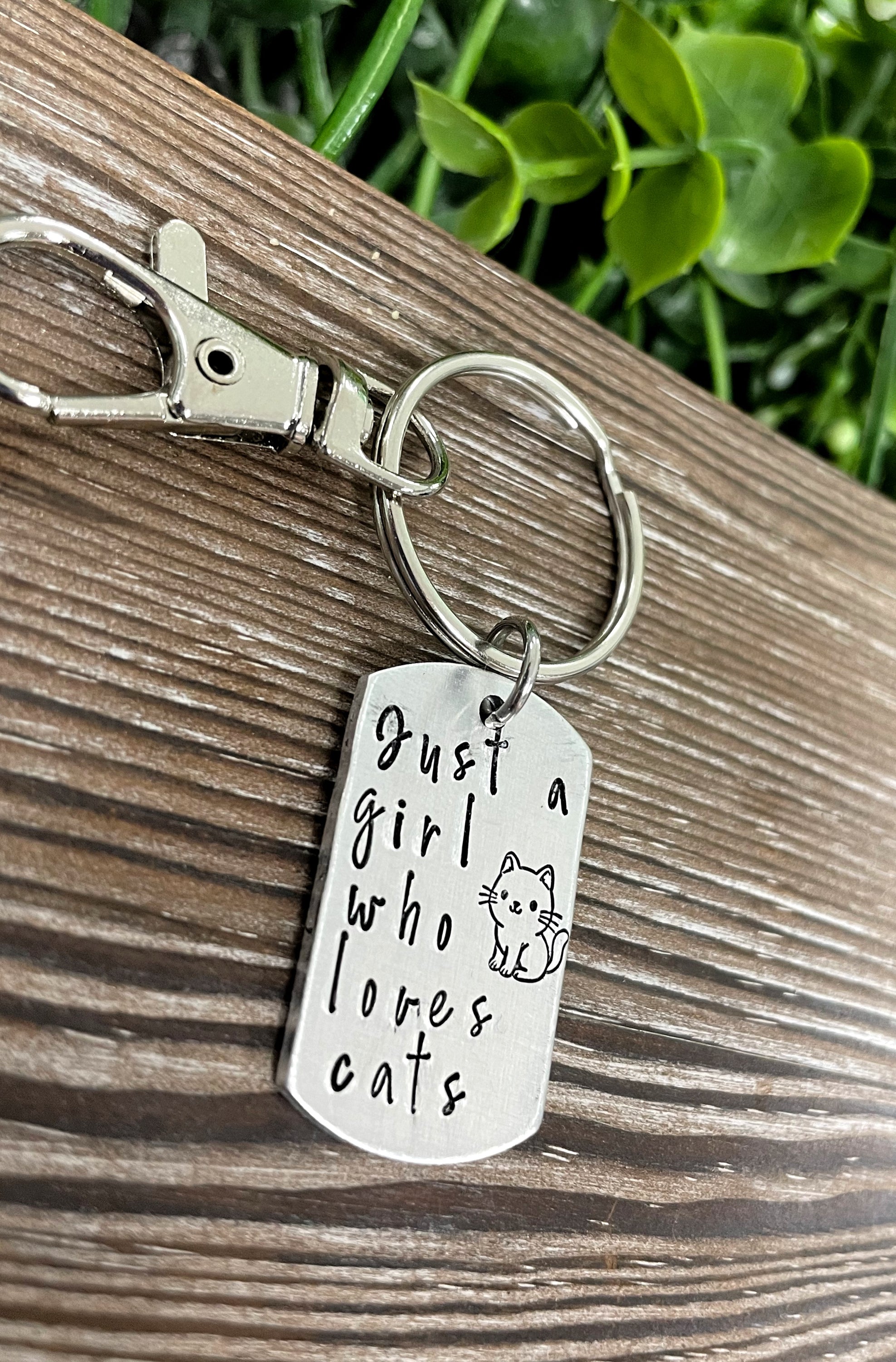 Hand-stamped key chain featuring the phrase 'Just a Girl Who Loves Cats', showcasing unique letter variations and a fun animal theme.