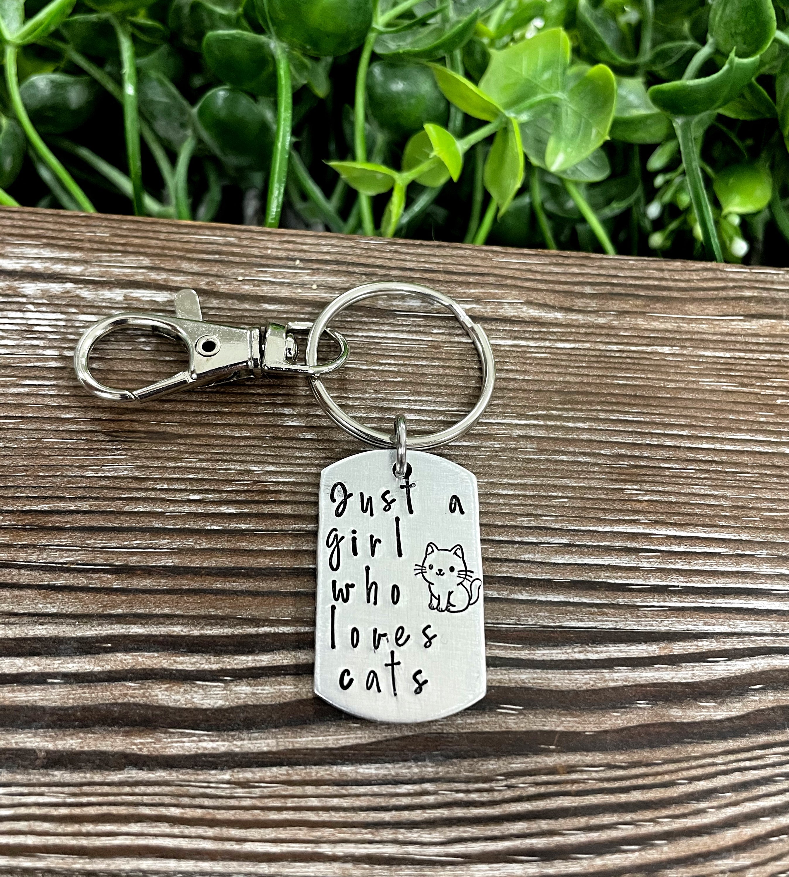 Hand-stamped key chain featuring the phrase 'Just a Girl Who Loves Cats', showcasing unique letter variations and a fun animal theme.