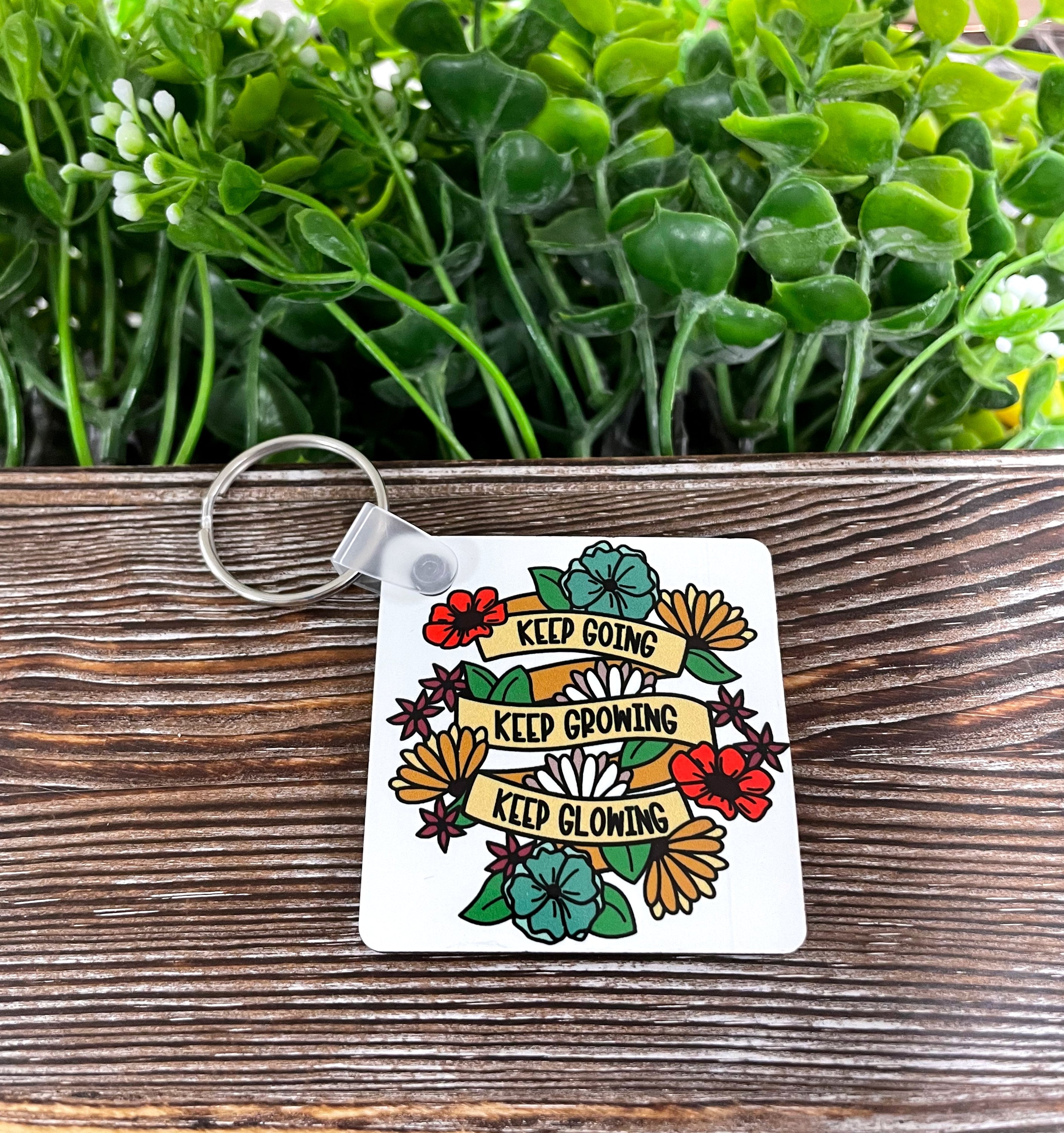 A colorful MDF square keychain featuring the phrase 'Keep Going Keep Growing Keep Glowing', showcasing a boho design.