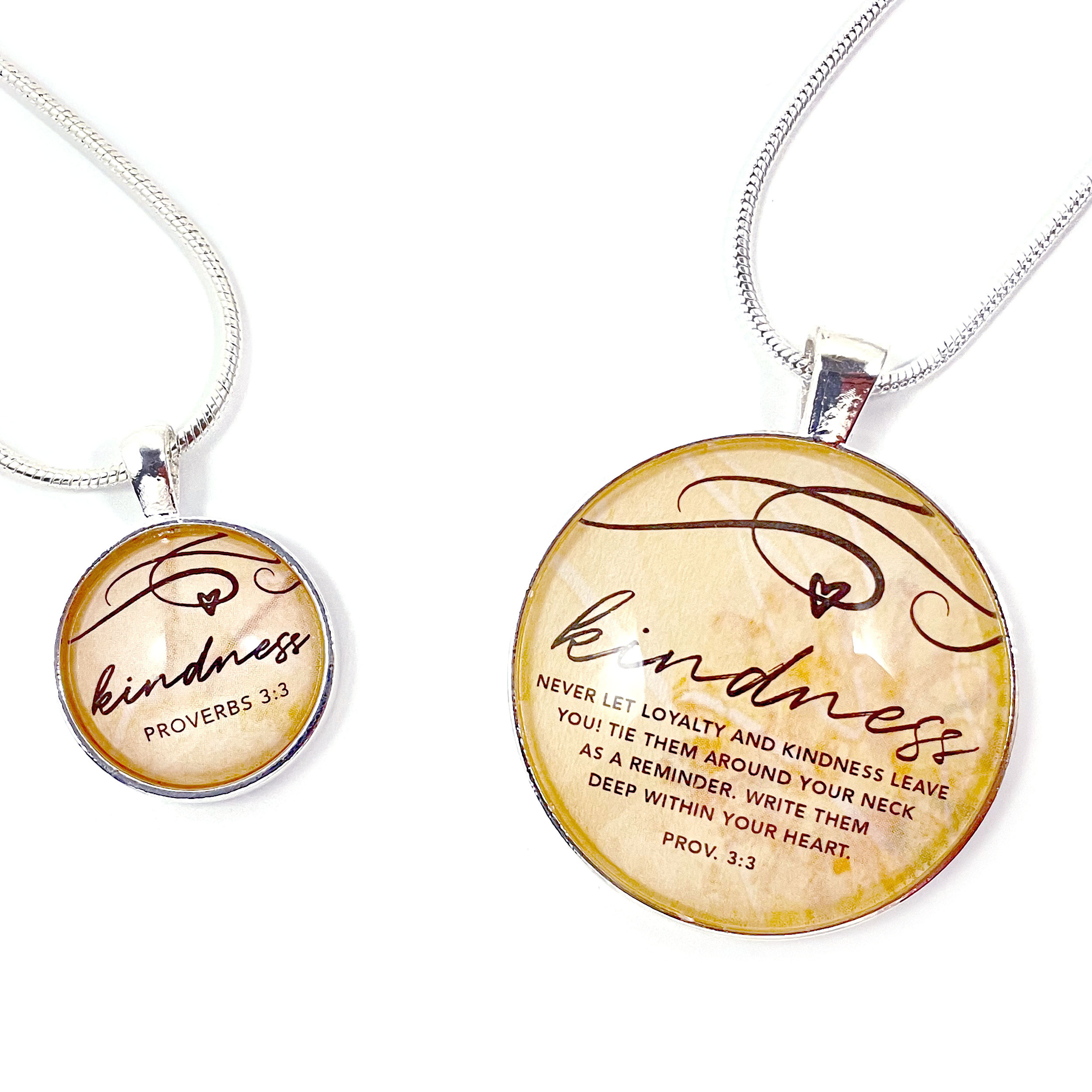 Silver-plated pendant necklace featuring the word 'Kindness' and Proverbs 3:3 scripture, with a heart illustration under glass.