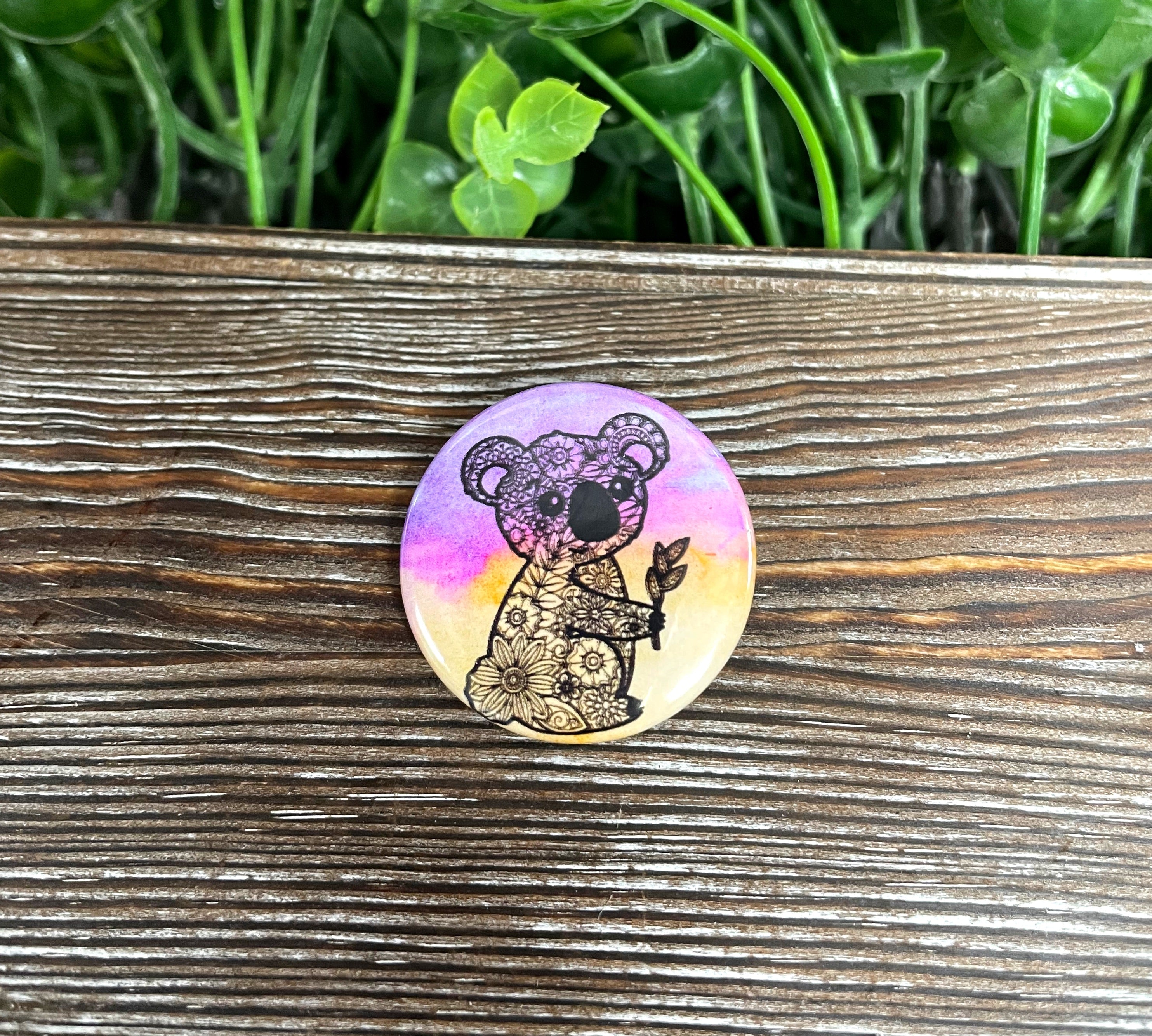 Koala Mandala graphic art button in purple and orange, measuring 1.25 inches, showcasing a vibrant mandala design.