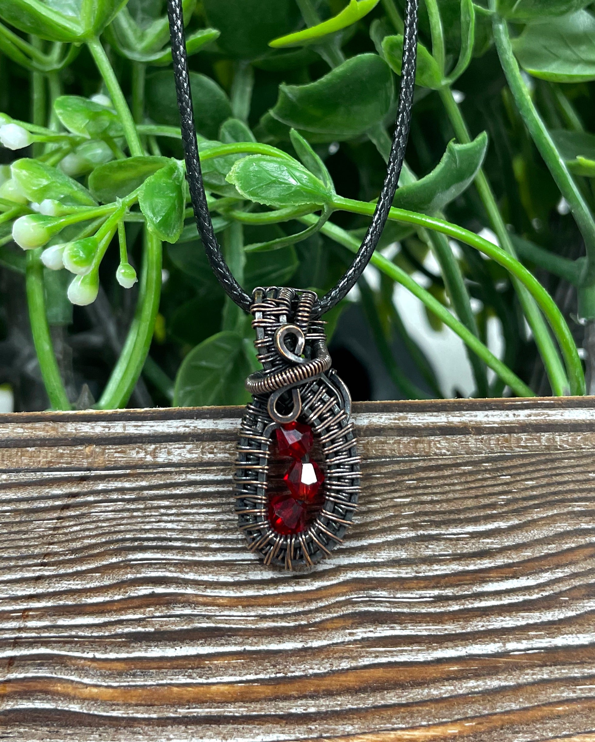 Mini wire wrapped pendant featuring three red glass crystals elegantly wrapped in argentium sterling silver wire on a 24-inch snake chain.