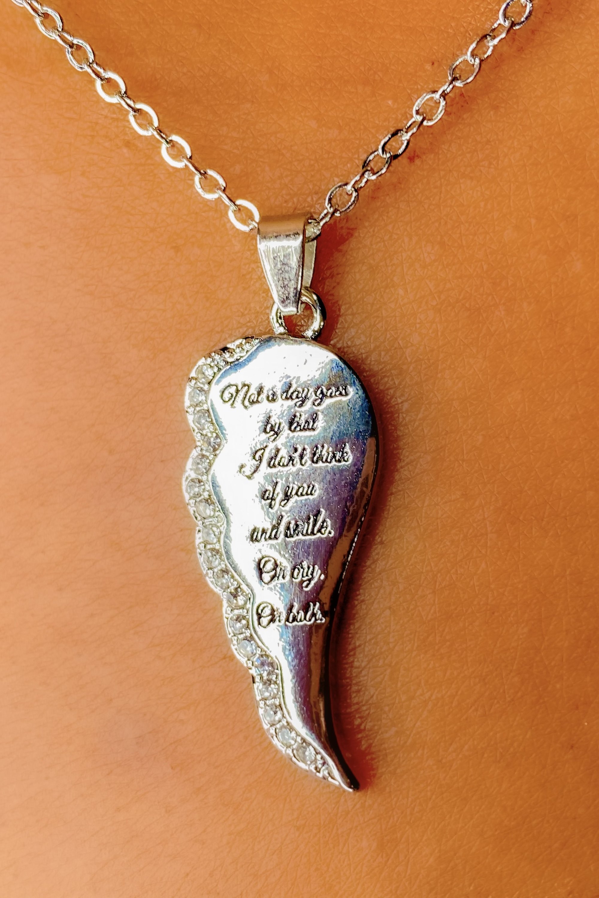 A silver remembrance necklace with the inscription 'Not A day goes by that I don’t think of you and smile. Or cry. Or both.' elegantly displayed.