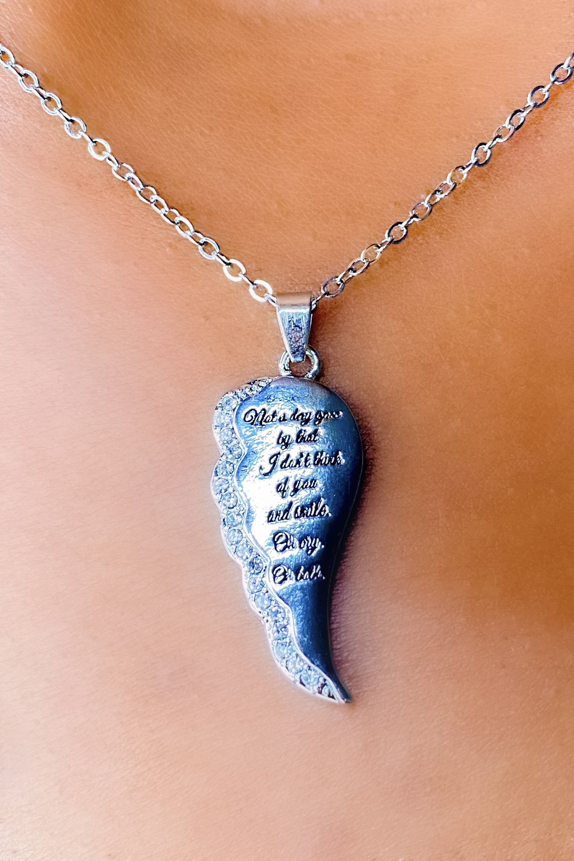 A silver remembrance necklace with the inscription 'Not A day goes by that I don’t think of you and smile. Or cry. Or both.' elegantly displayed.