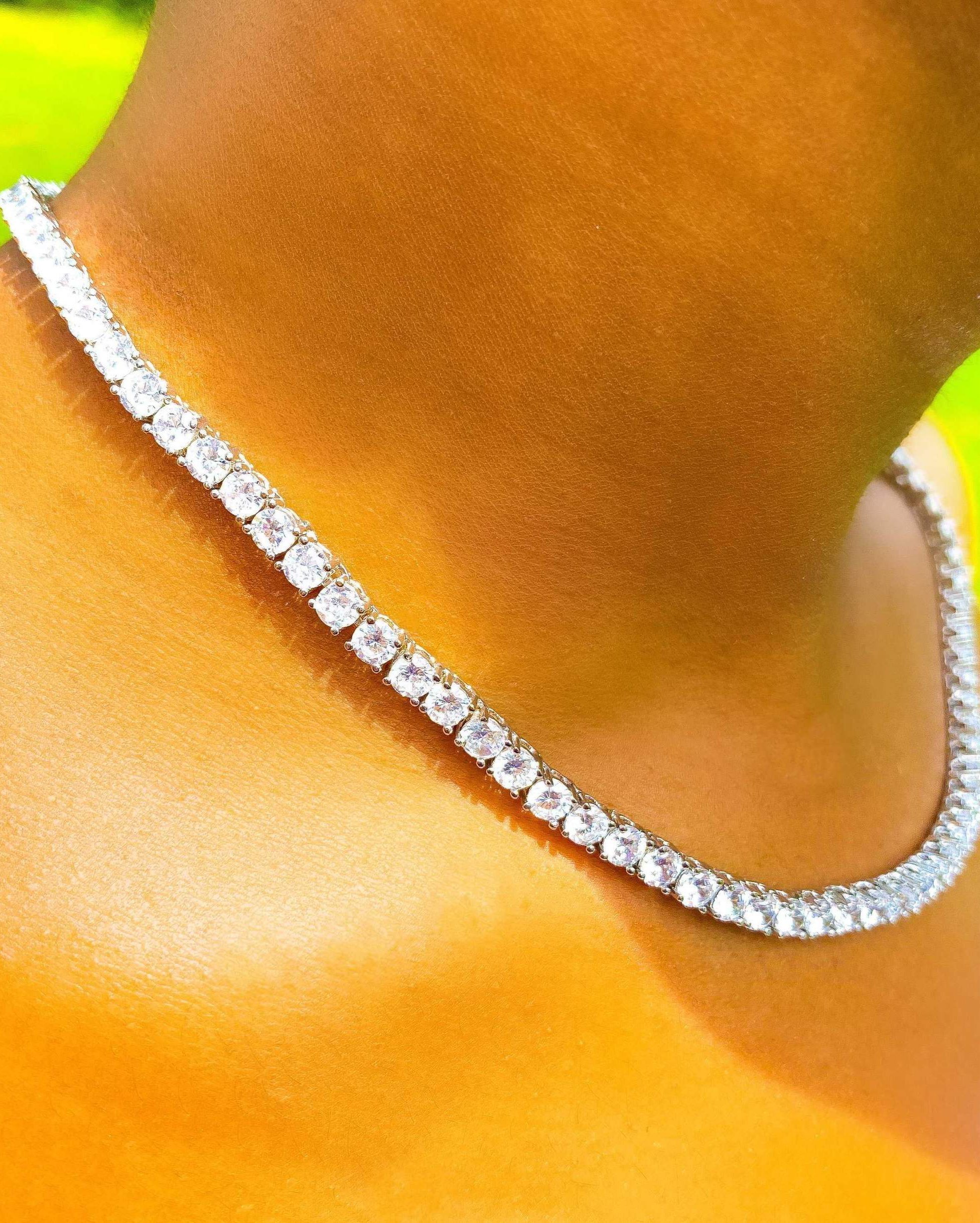 So Icy Tennis Necklace featuring a 4mm row design in high polished 14K white gold with flawless VVS simulants, available in silver and gold.