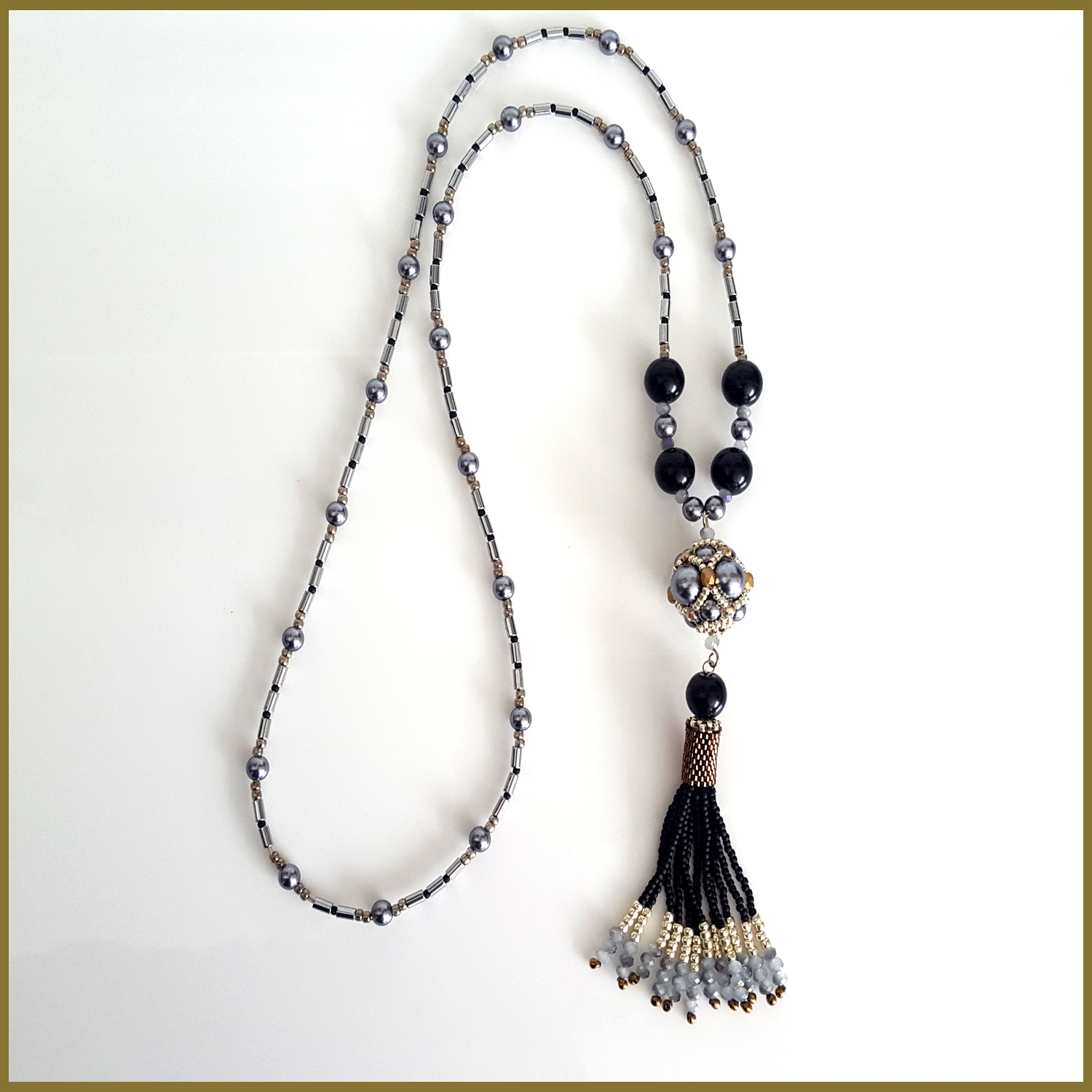 A stunning black beaded tassel necklace featuring silver hematite tubes, handmade with Toho and Delica seed beads, showcasing a boho chic design.