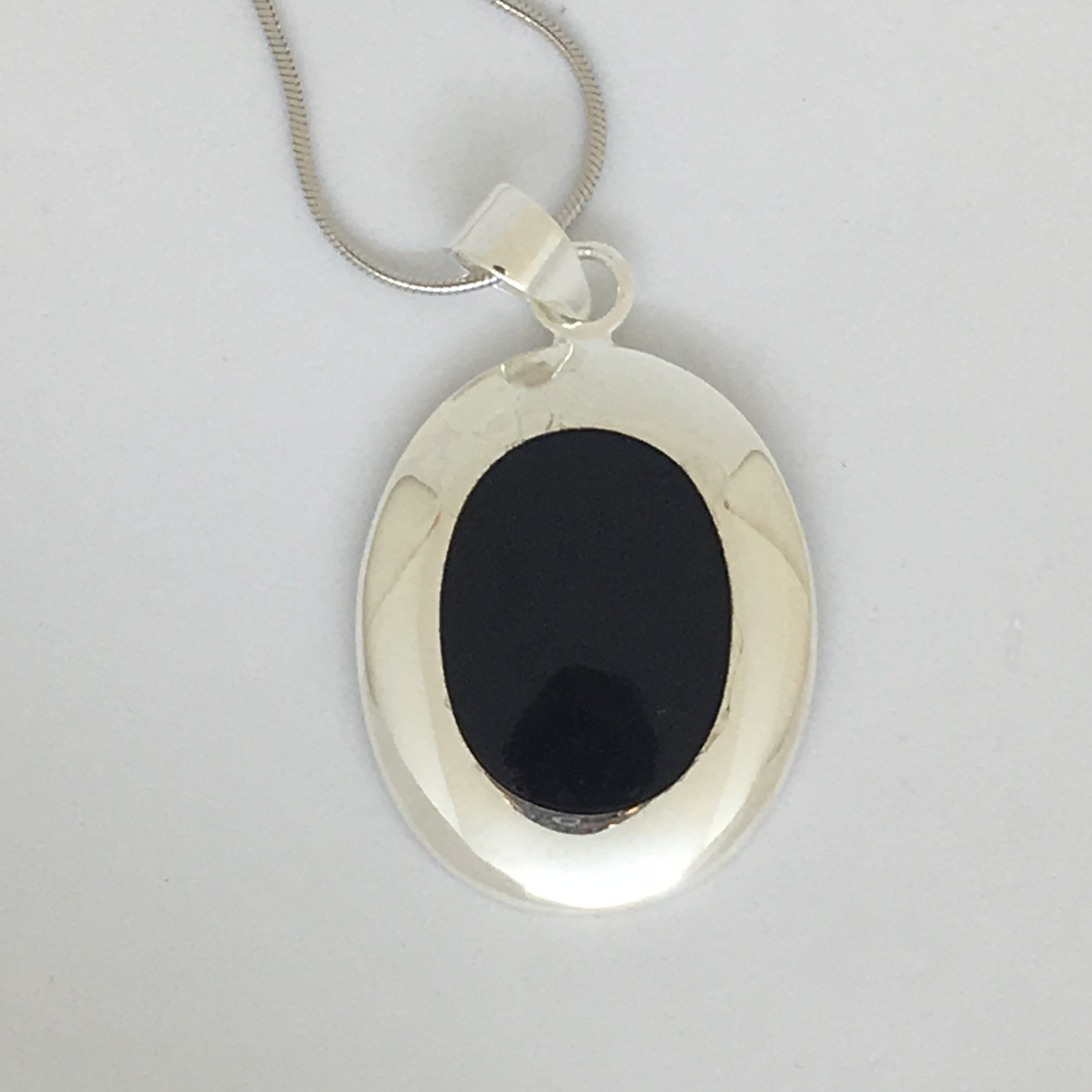 Onix Pendant featuring a deep black Onix stone encased in a 925 sterling silver pendant, displayed on a silver necklace cord.