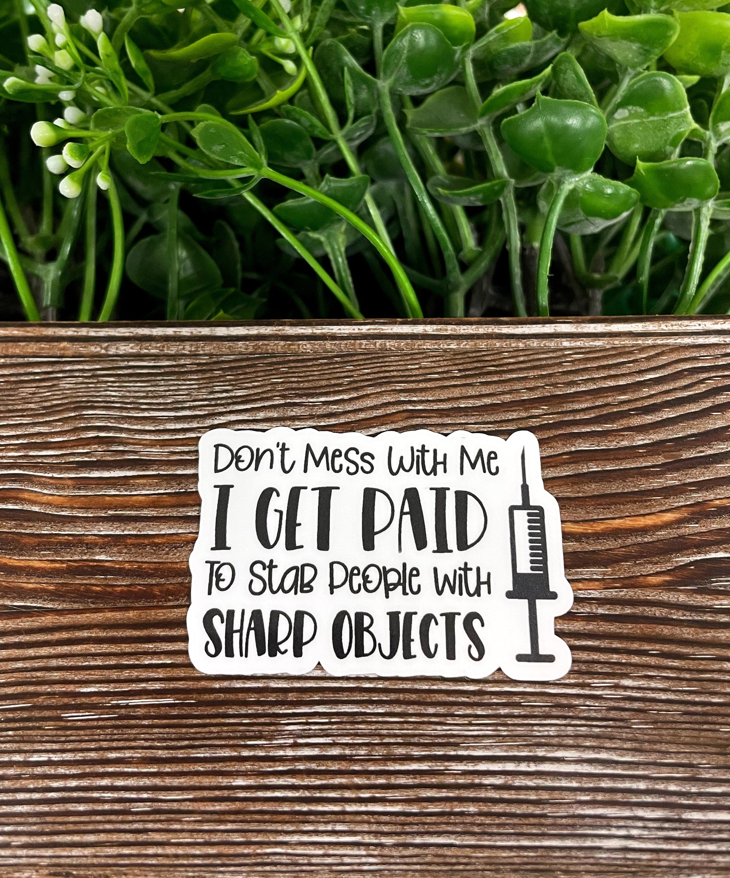 A vibrant die cut vinyl sticker featuring the phrase 'Paid to Stab People w/ Sharp Objects' with a boho design, perfect for personalizing items.