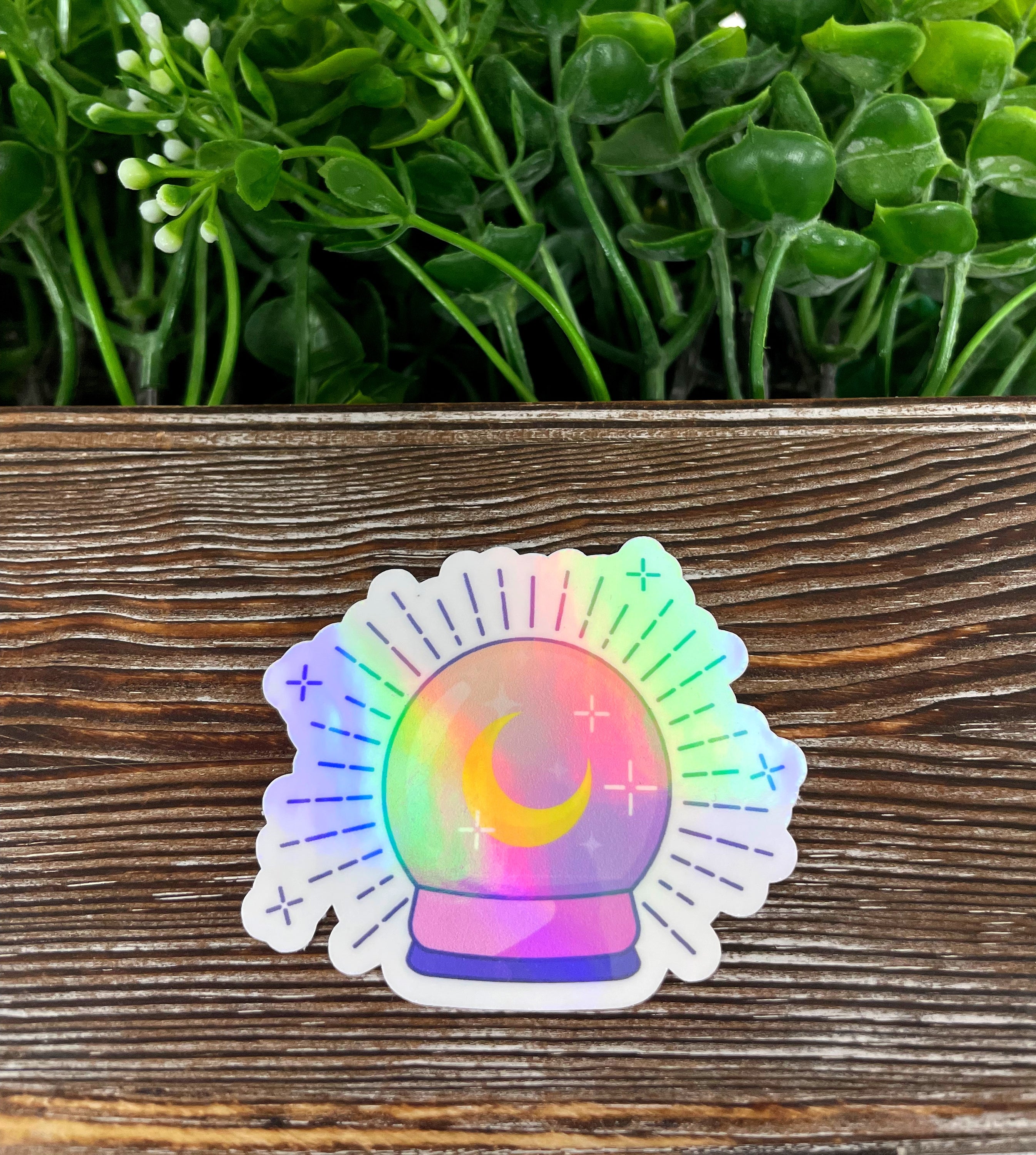 A vibrant pastel crystal ball die cut sticker on a smooth surface, showcasing its colorful design and water-resistant laminate finish.