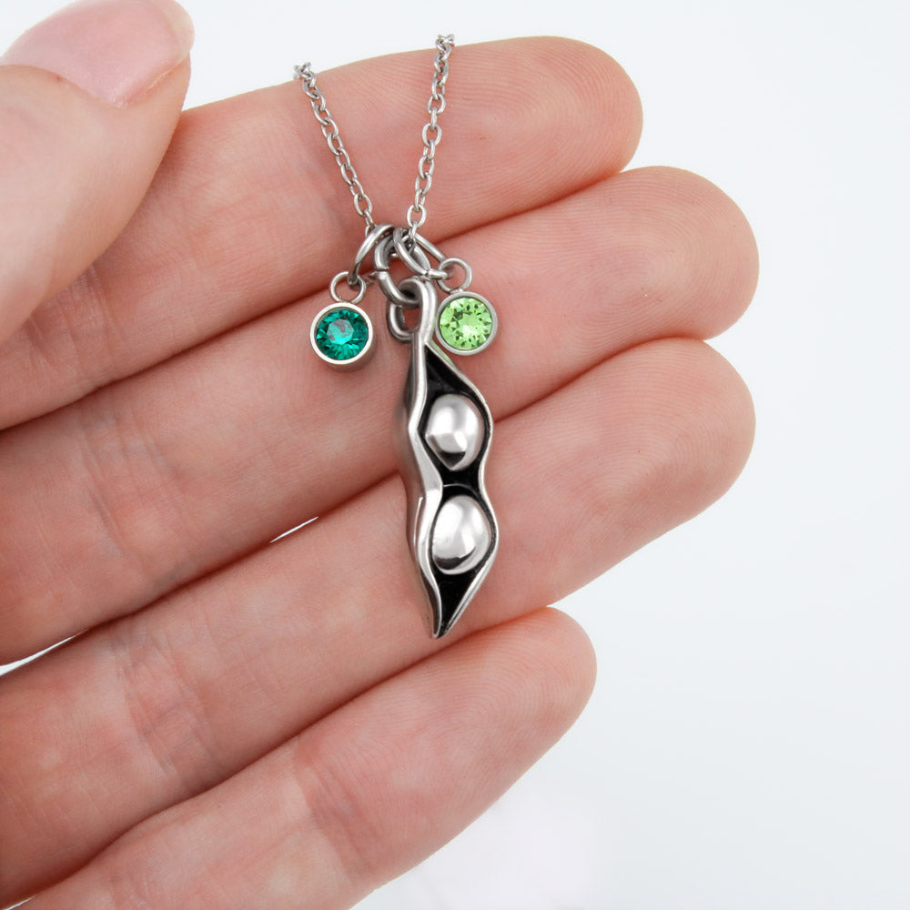 A beautiful Peas In A Pod Necklace featuring customizable peas and sparkling Swarovski® birthstones, crafted in 14K White Gold over Stainless Steel.