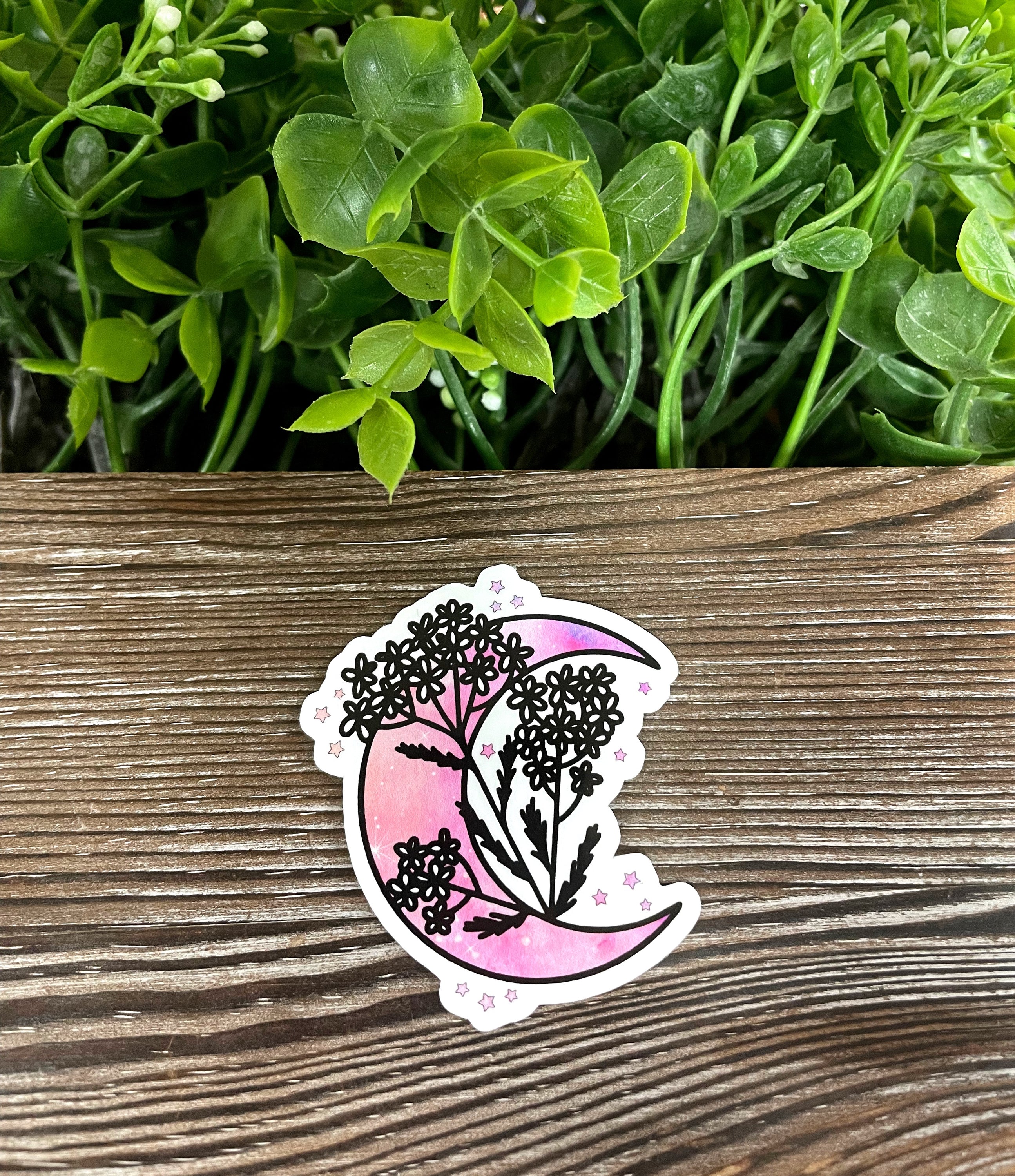 A vibrant pink crescent moon sticker adorned with colorful flowers, showcasing a whimsical design perfect for personalizing various items.