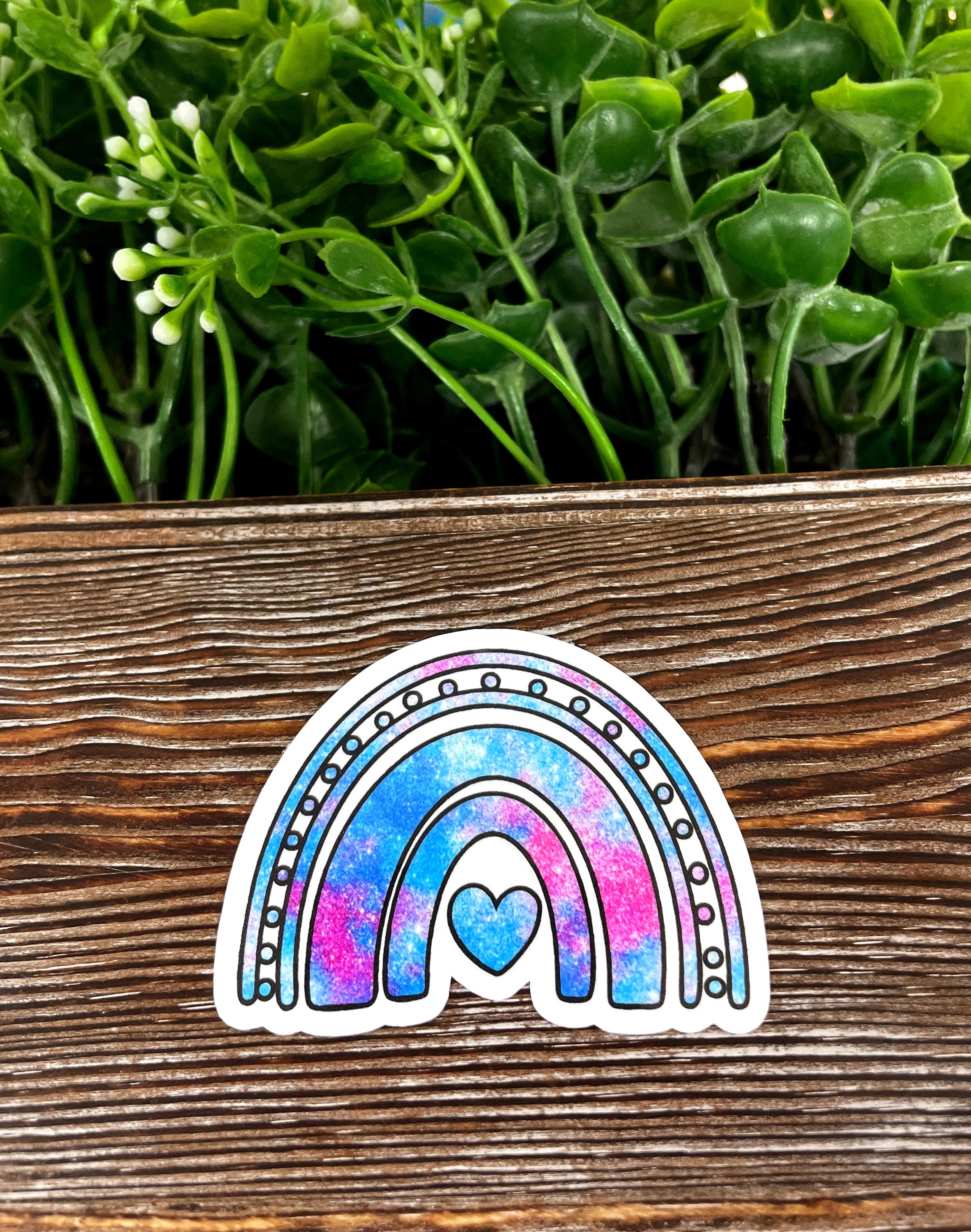 Purple and blue galaxy rainbow die cut vinyl sticker on a smooth surface, showcasing vibrant colors and intricate design.