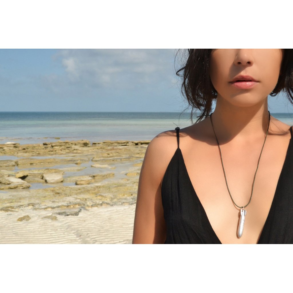 Recycled Bomb Pendant Necklace made from aluminum bomb parts, featuring an adjustable cord in olive green, black, or red, symbolizing peace and resilience.