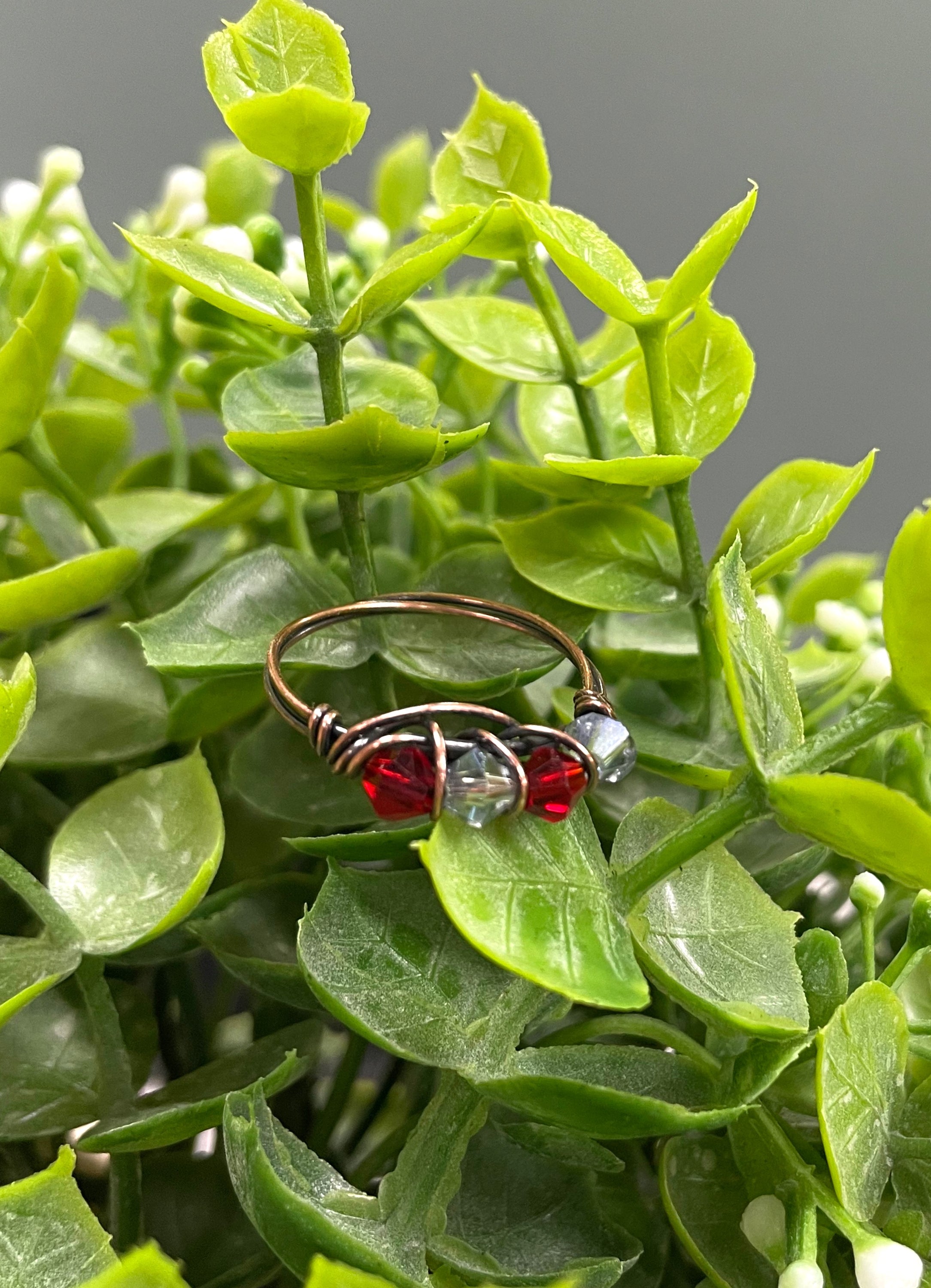 A beautifully handcrafted Red and Grey Glass Crystal Wire Wrapped Ring featuring vibrant glass beads wrapped in oxidized copper wire.