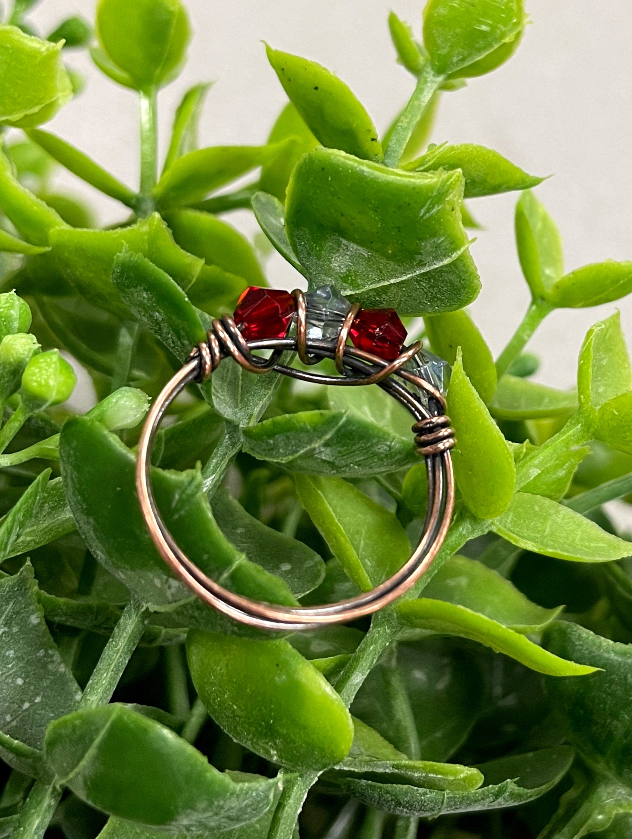 A beautifully handcrafted Red and Grey Glass Crystal Wire Wrapped Ring featuring vibrant glass beads wrapped in oxidized copper wire.