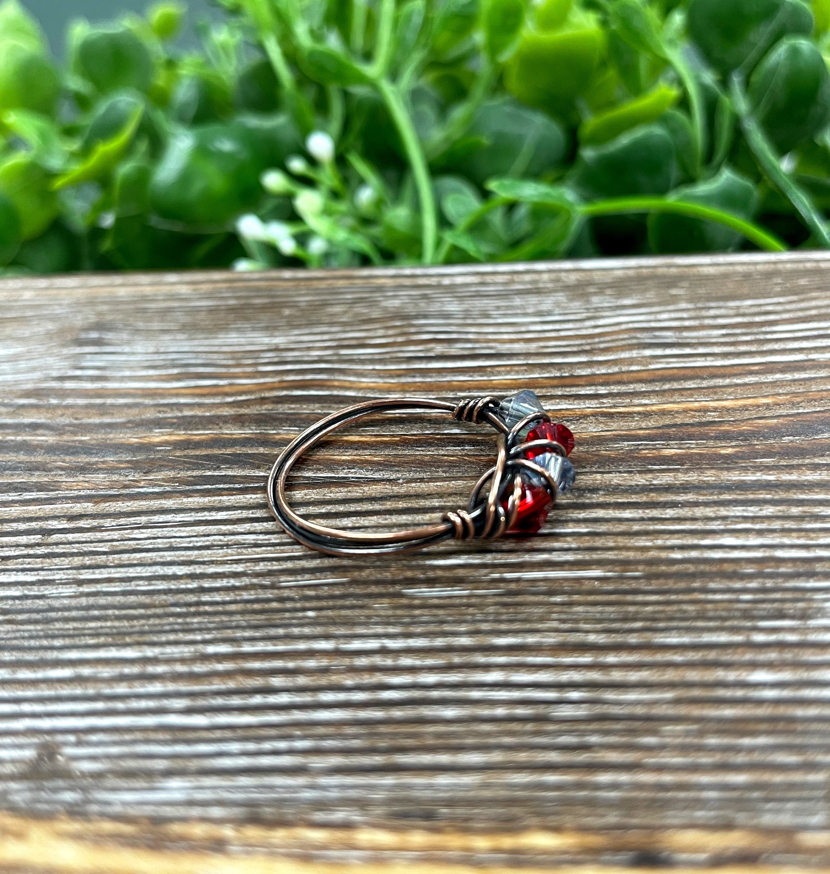 A beautifully handcrafted Red and Grey Glass Crystal Wire Wrapped Ring featuring vibrant glass beads wrapped in oxidized copper wire.