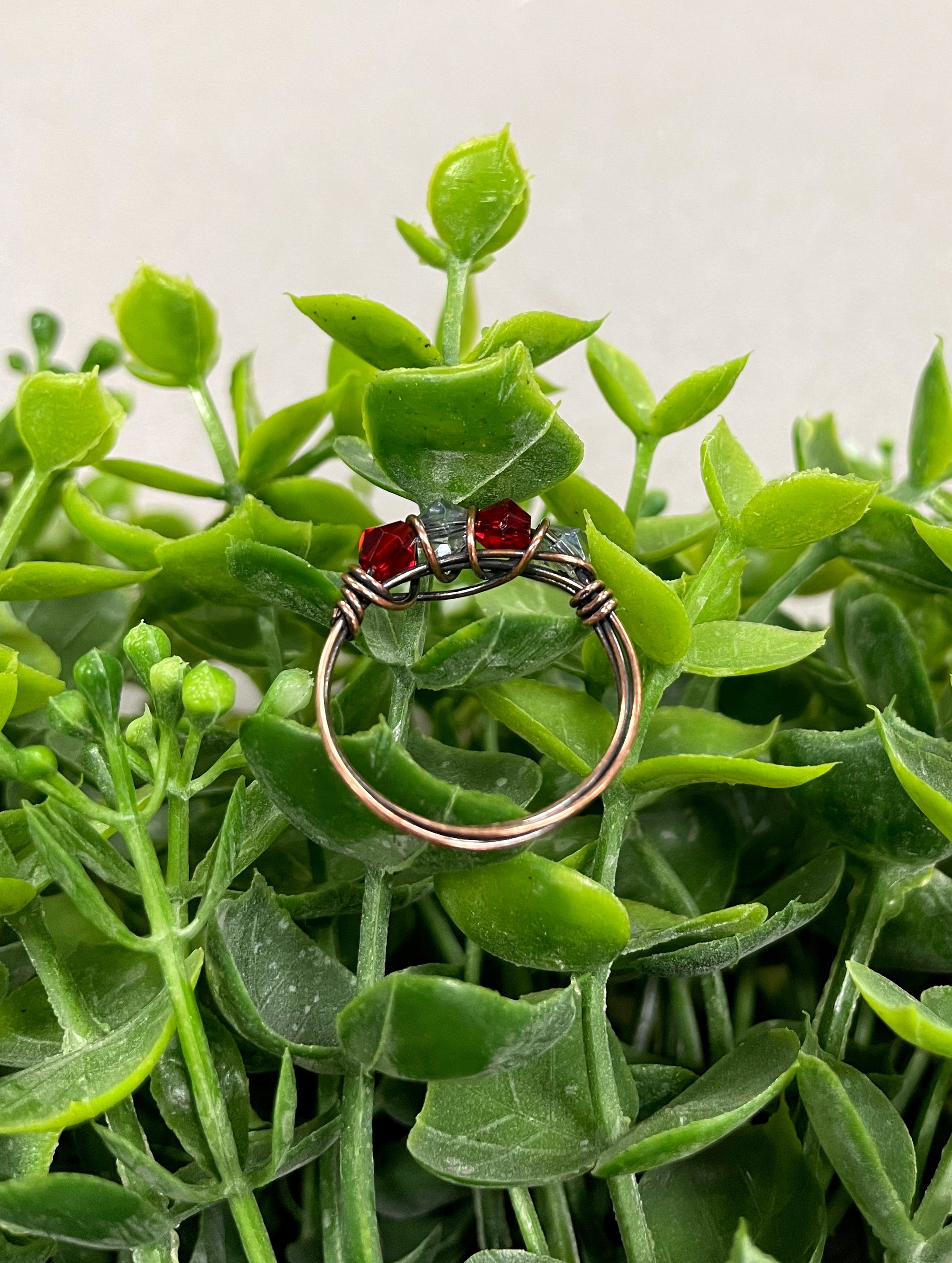 A beautifully handcrafted Red and Grey Glass Crystal Wire Wrapped Ring featuring vibrant glass beads wrapped in oxidized copper wire.