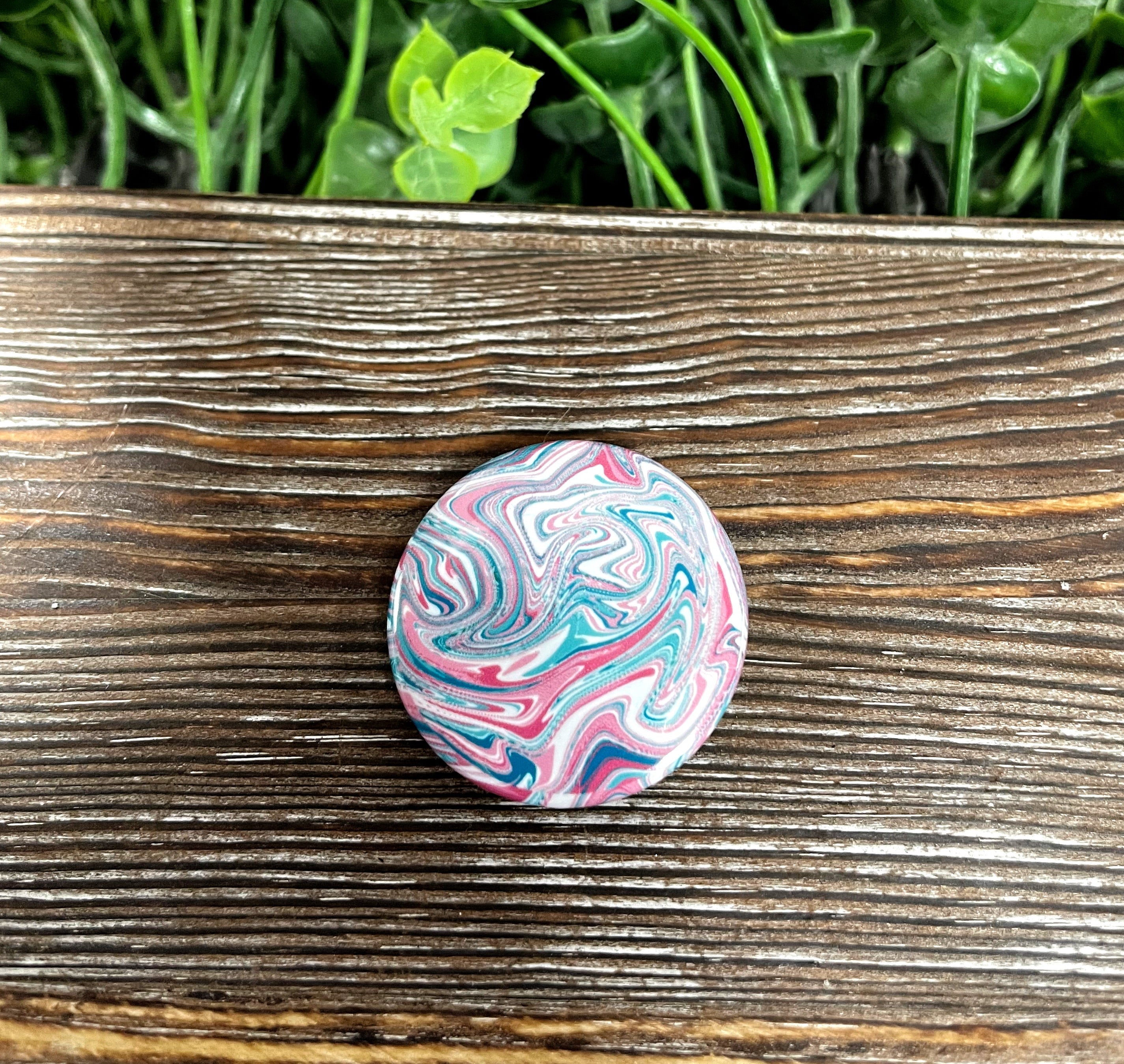 A vibrant 1.25-inch button featuring a red, blue, and white swirl design, perfect for personalizing bags and accessories.