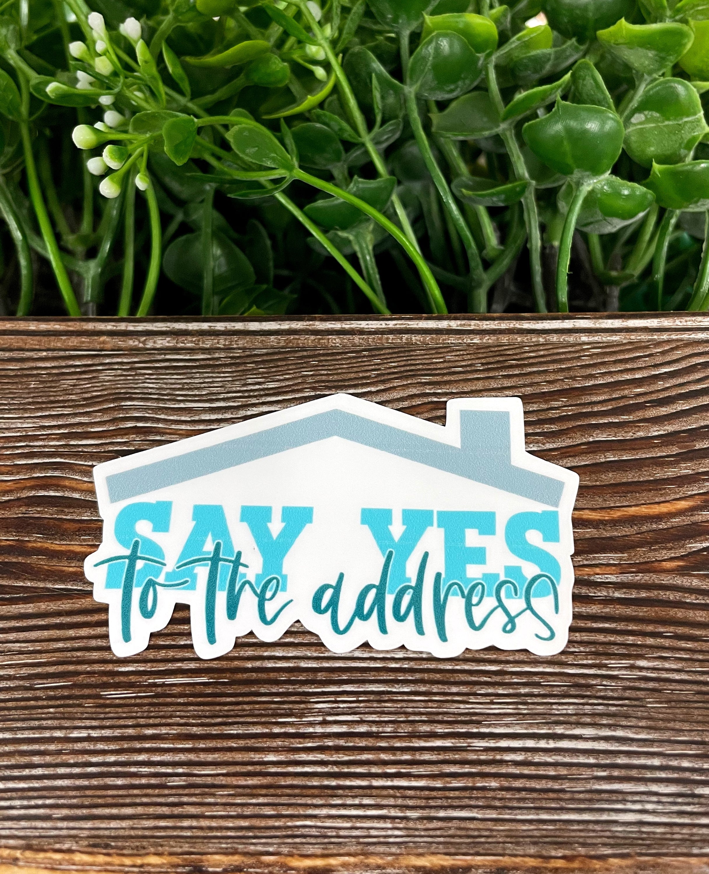 Say Yes to the Address Real Estate Die Cut Vinyl Sticker on a smooth surface, showcasing vibrant colors and a unique design.