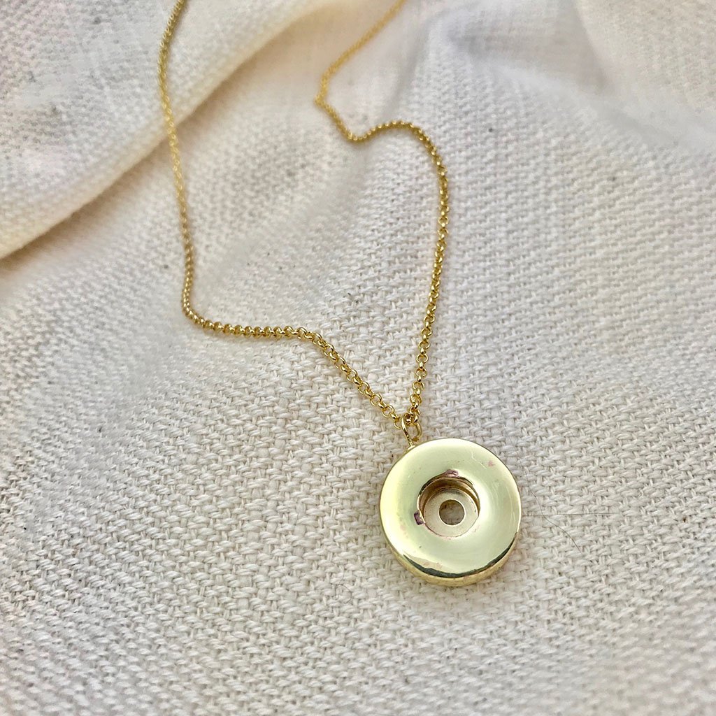 A stylish Shell Casing Pendant Necklace made from recycled bullet casings, featuring a gold plated chain, showcasing unique craftsmanship.