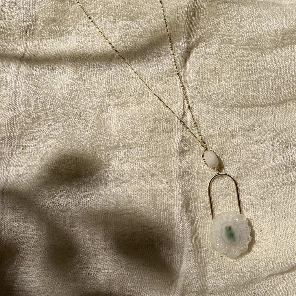 A beautifully crafted Solar Quartz Eye Necklace featuring a polished solar quartz stone and moon stone on a brass chain, showcasing unique colors and patterns.