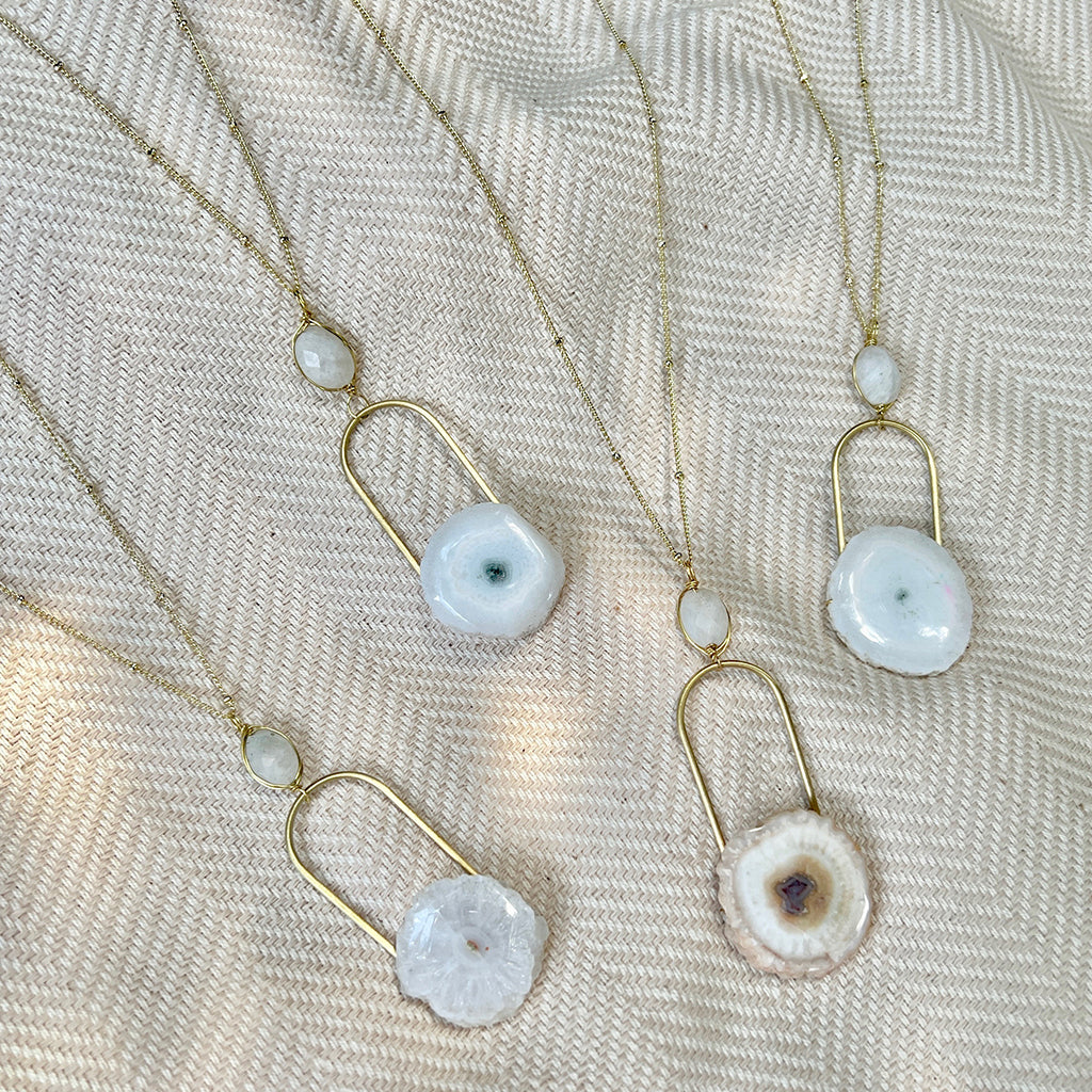 A beautifully crafted Solar Quartz Eye Necklace featuring a polished solar quartz stone and moon stone on a brass chain, showcasing unique colors and patterns.