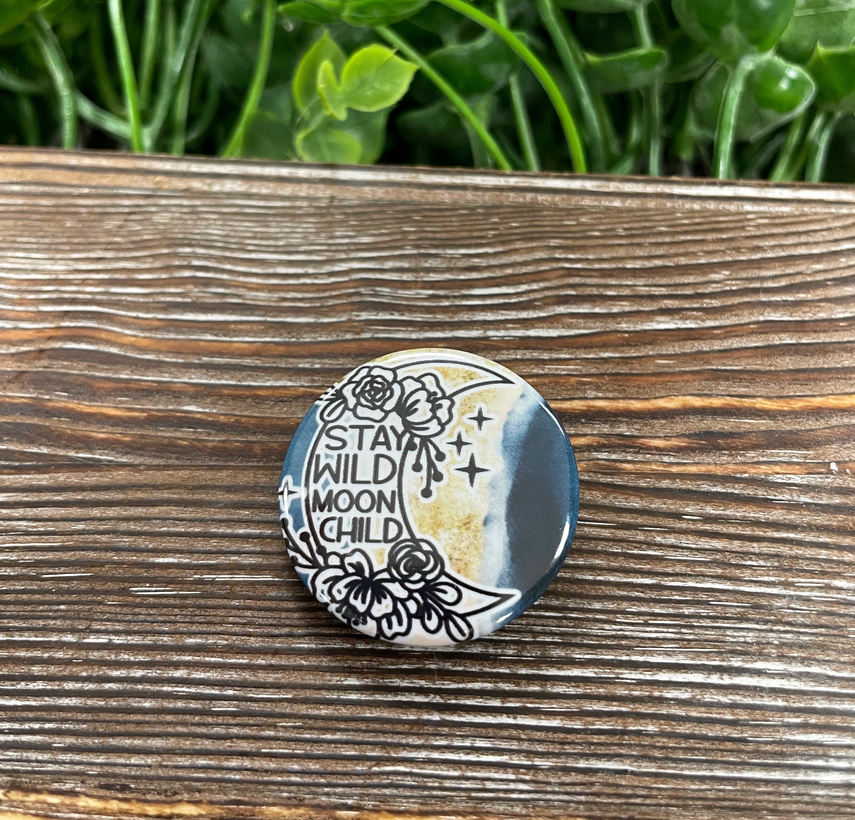 Stay Wild Moon Child graphic art button in blue and gold, measuring 1.25 inches, showcasing a vibrant design.