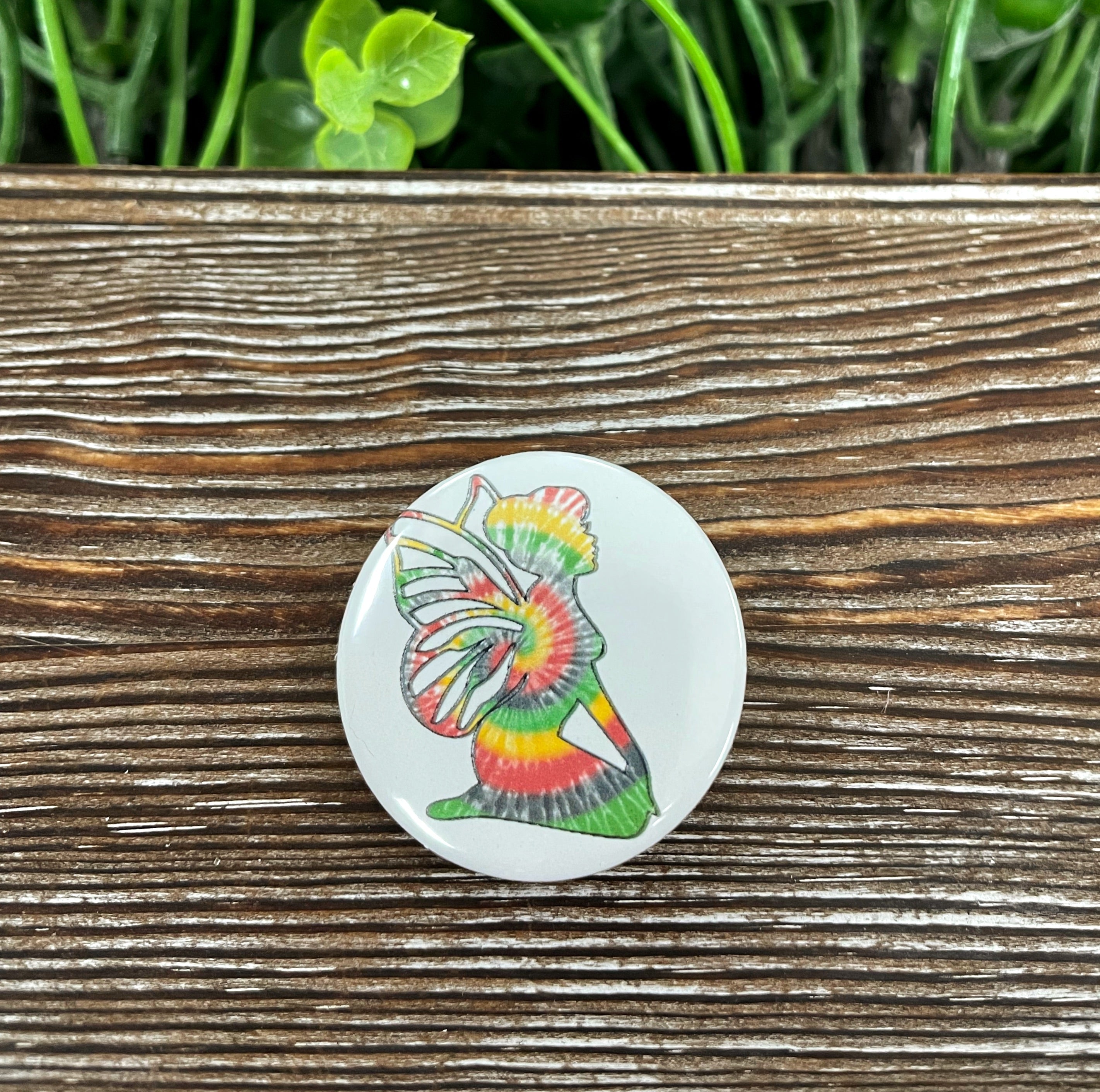 A colorful 1.25-inch tie dye fairy graphic art button with a plastic back, showcasing vibrant colors and whimsical design.