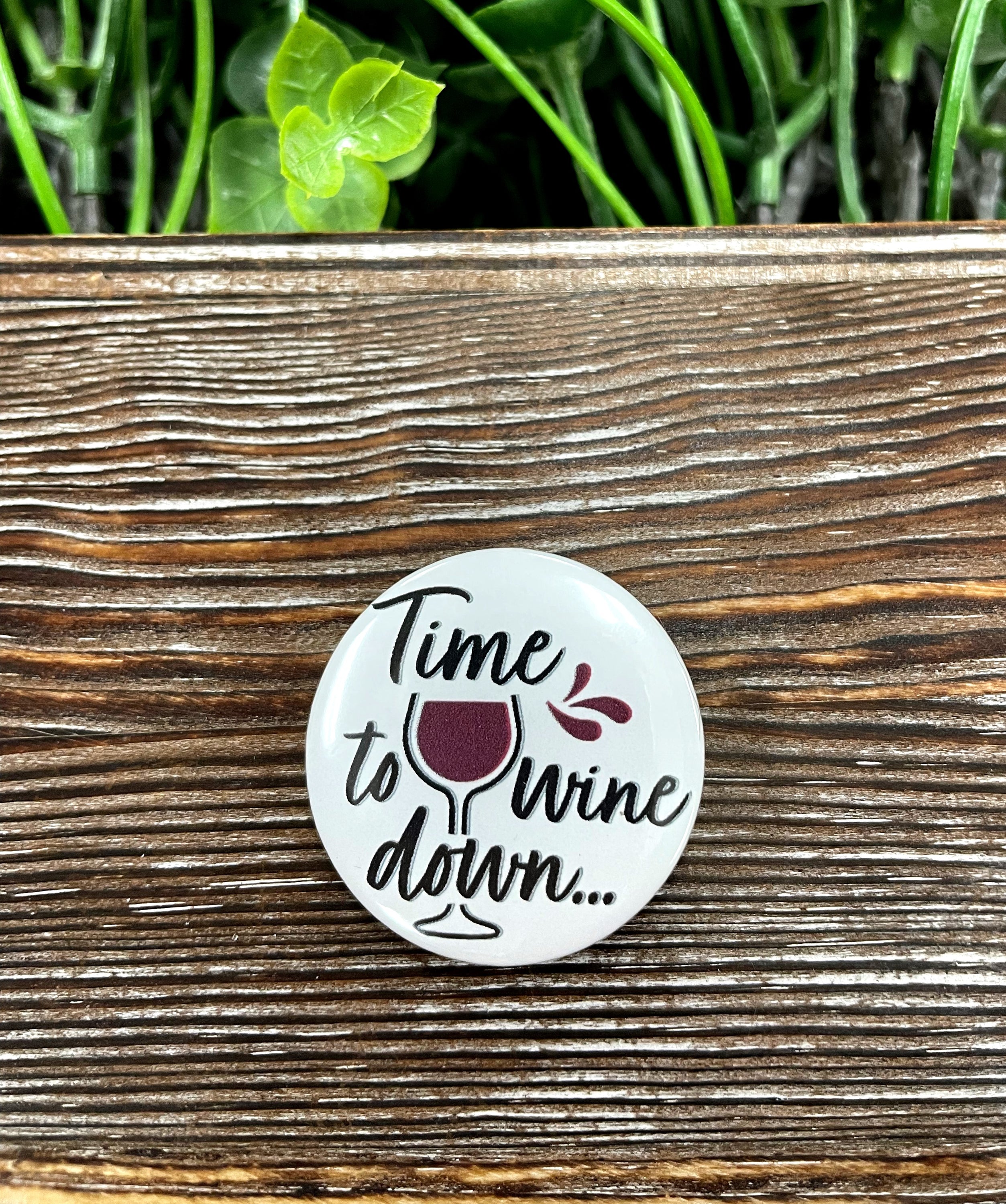 A vibrant 1.25-inch Time to Wine Down graphic art button featuring a playful wine-themed design, perfect for accessories.