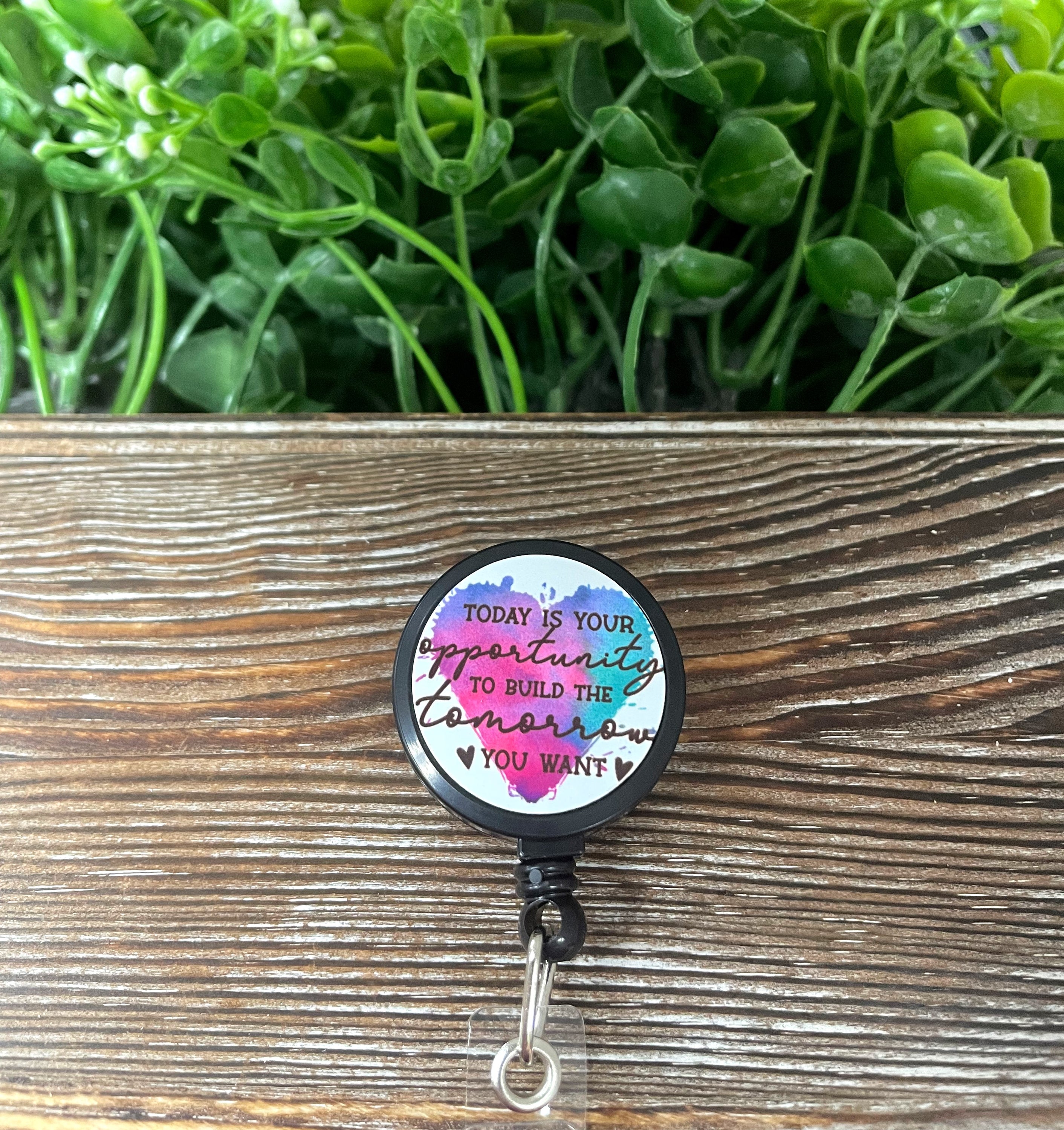 Retractable badge reel featuring a colorful metal design, measuring 1.2 inches in diameter with a 24-inch extension cord.