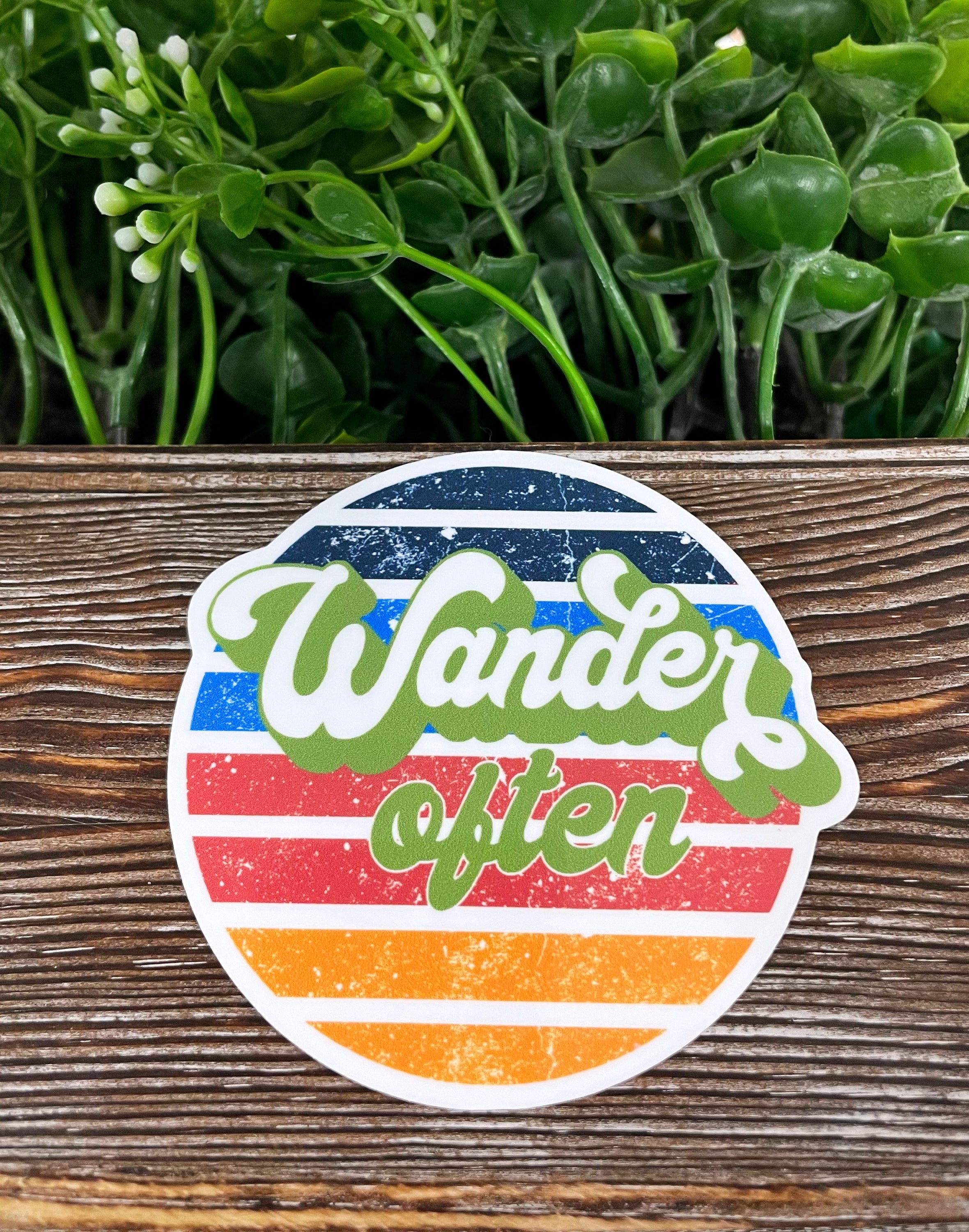 A vibrant die cut vinyl Travel Sticker featuring the phrase 'Wander Often', perfect for personalizing various surfaces.