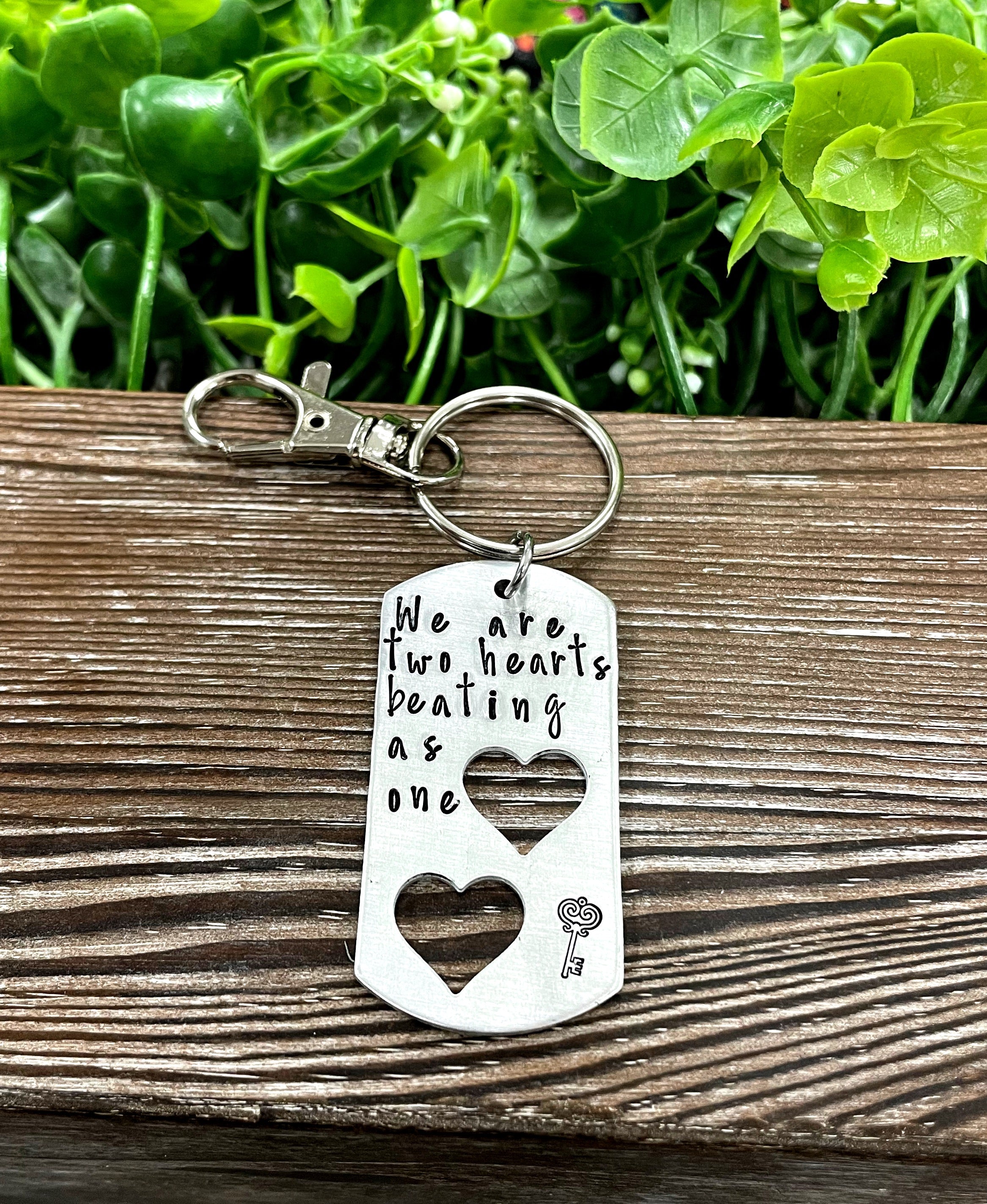 Hand-stamped keychain featuring the phrase 'We are two hearts beating as one', showcasing unique variations in design and craftsmanship.