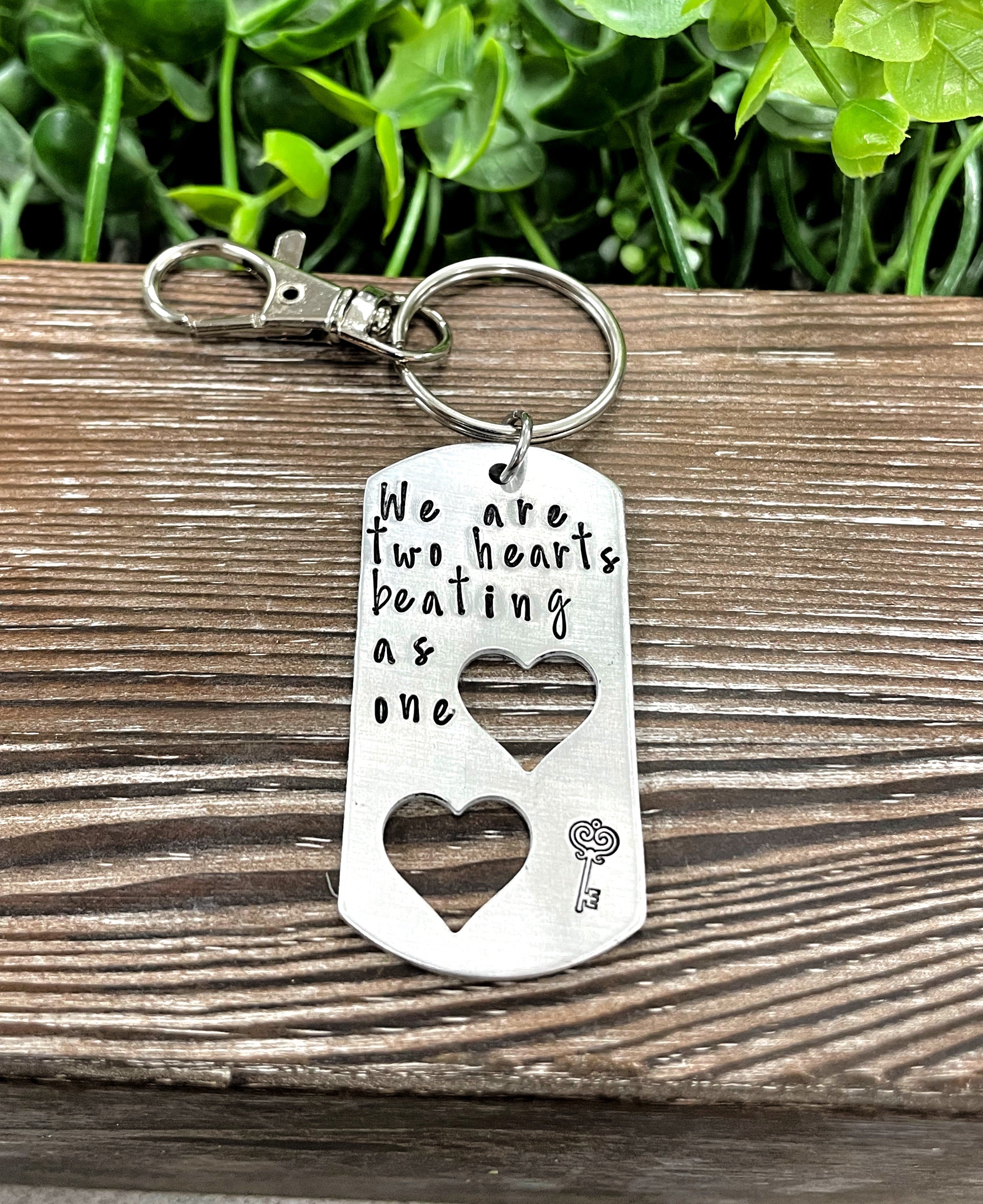 Hand-stamped keychain featuring the phrase 'We are two hearts beating as one', showcasing unique variations in design and craftsmanship.