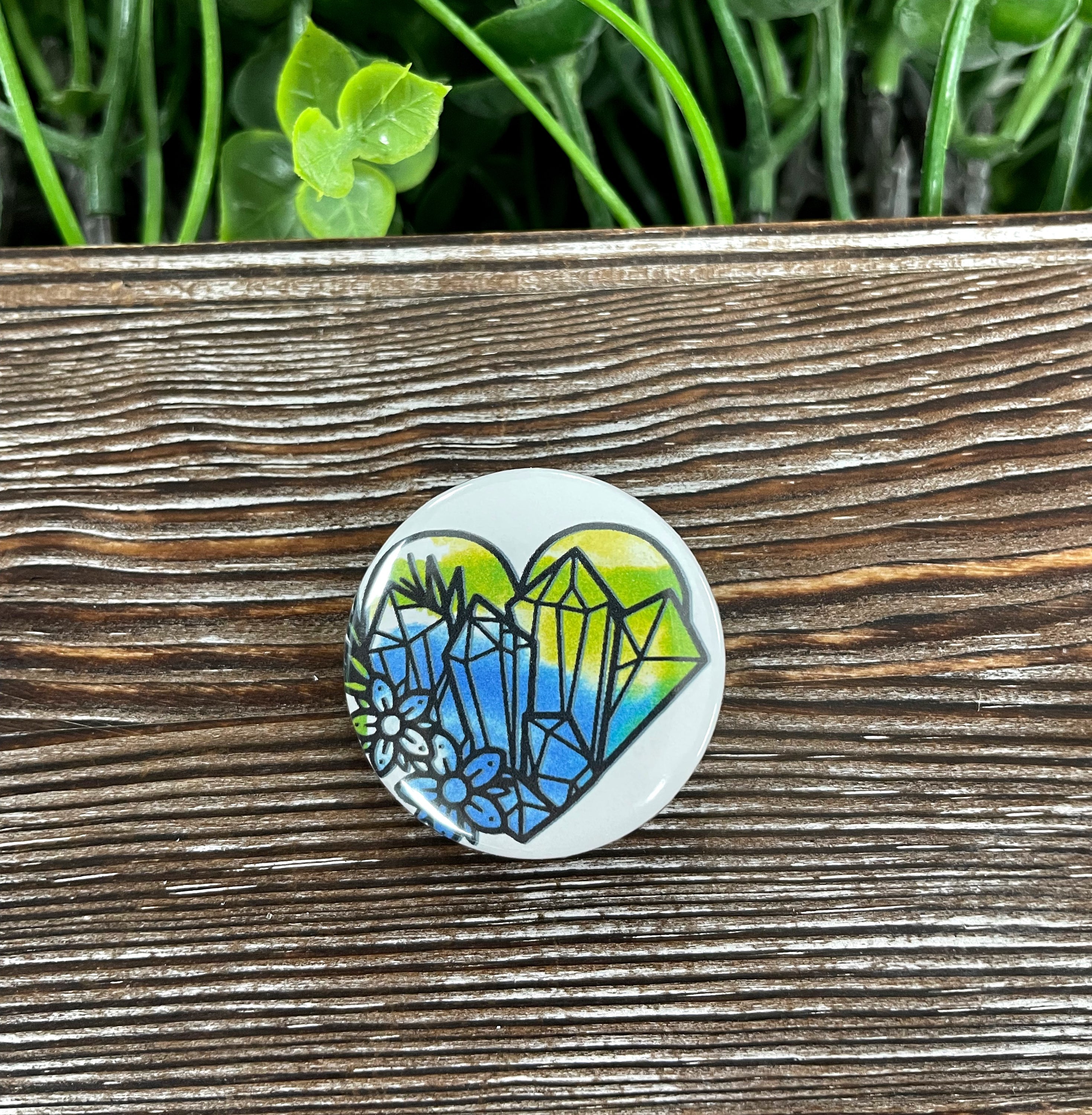 A colorful watercolor heart crystal gemstone cluster button pin, 1.25 inches in size, featuring a vibrant design on a durable plastic back.