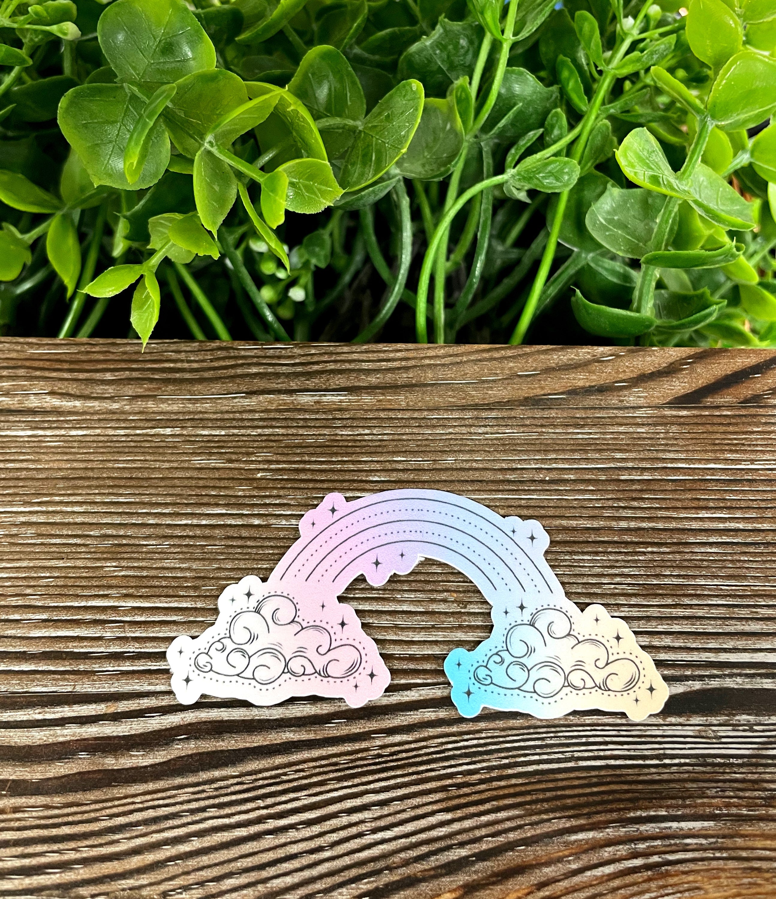 A vibrant watercolor pastel rainbow and clouds die cut vinyl sticker, showcasing colorful hues and whimsical design, perfect for personalizing items.