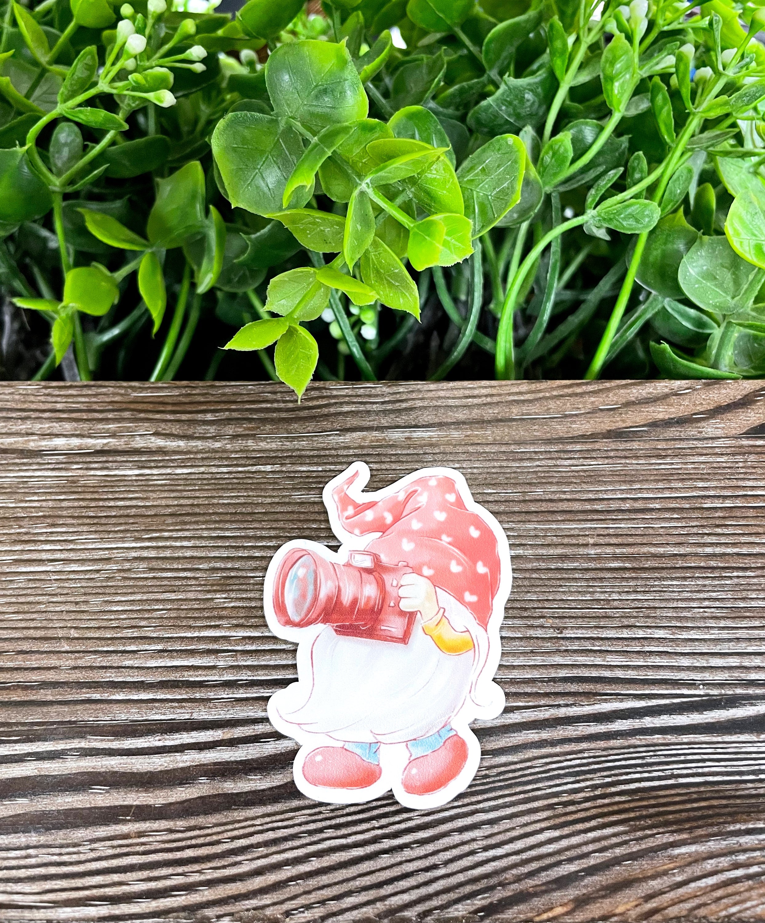 A vibrant die cut vinyl sticker featuring a watercolor gnome photographer, showcasing a whimsical design perfect for personalizing items.