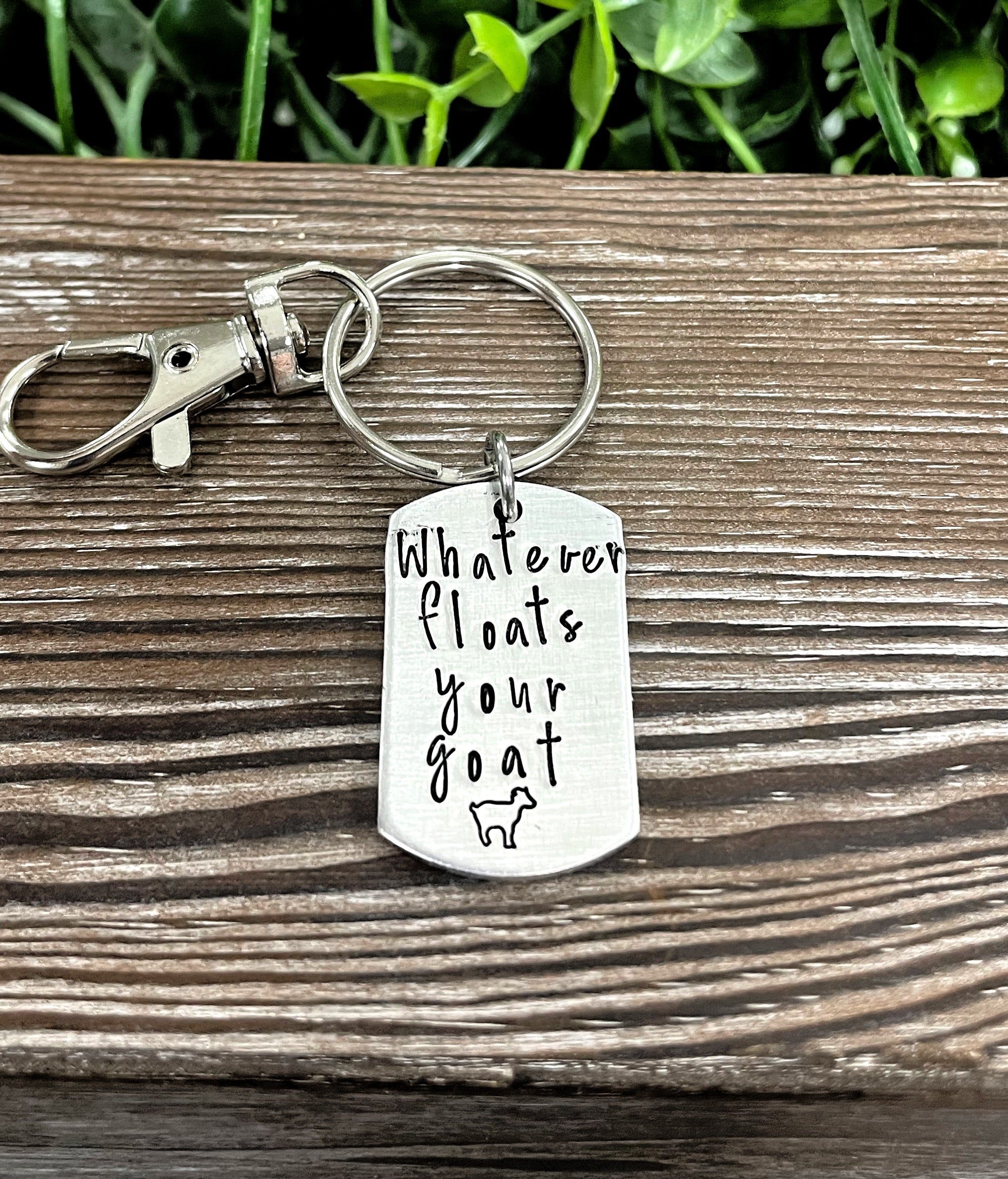 Hand-stamped key chain featuring the phrase 'Whatever floats your goat' with a fun animal theme, showcasing unique craftsmanship.