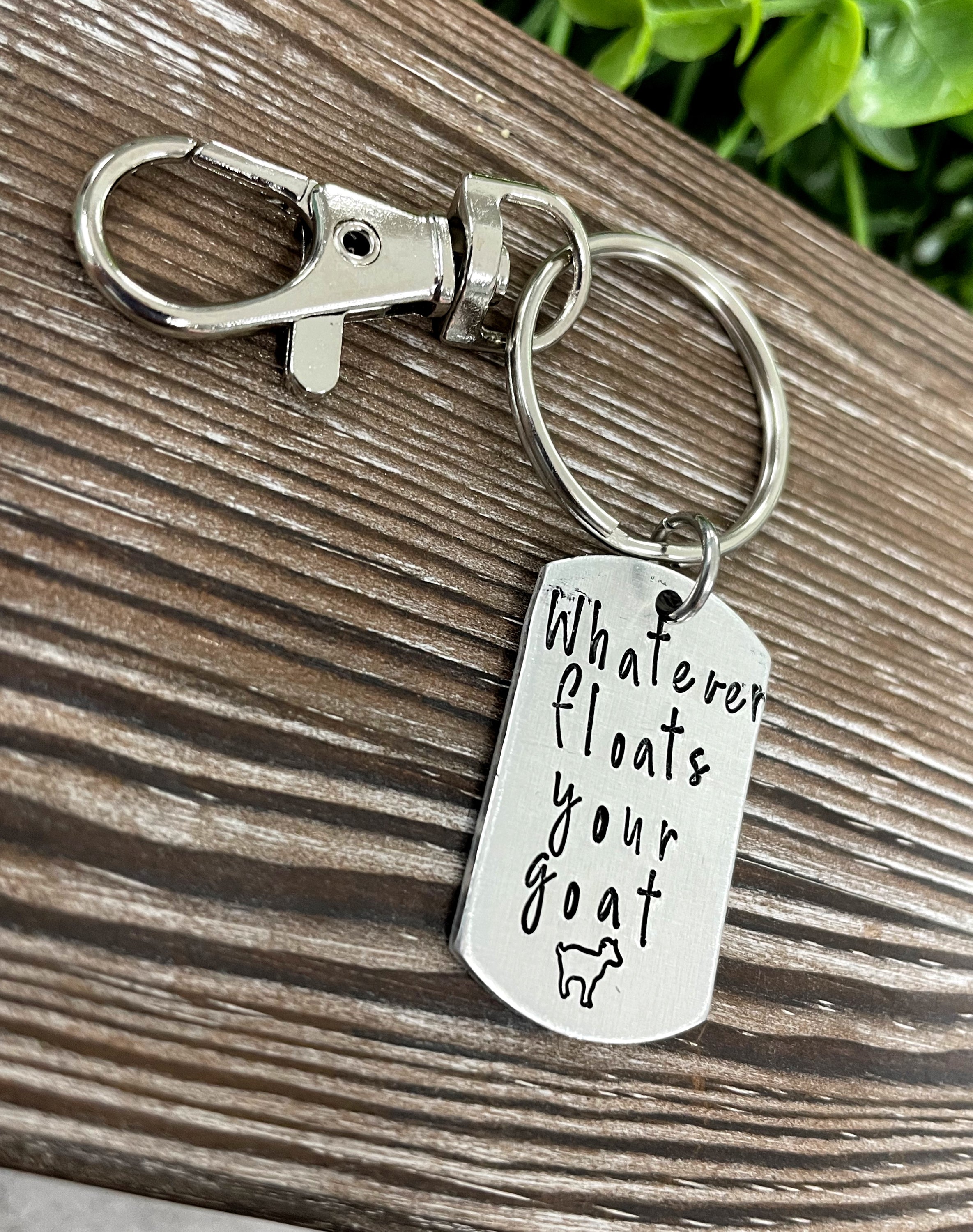 Hand-stamped key chain featuring the phrase 'Whatever floats your goat' with a fun animal theme, showcasing unique craftsmanship.