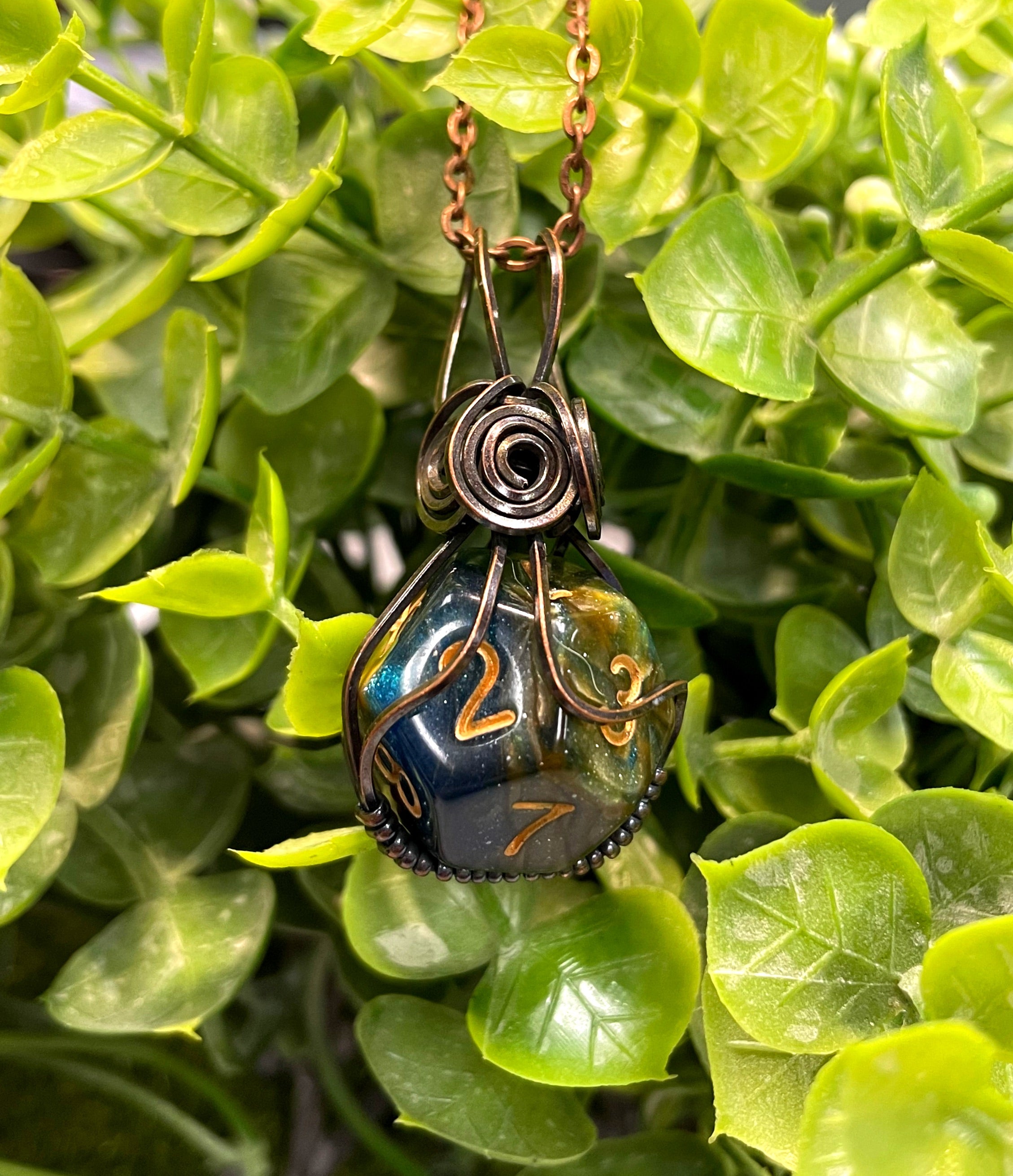 Wire Wrapped D12 Dice Pendant featuring a blue D10 dice wrapped in oxidized copper wire on a suede leather cord.