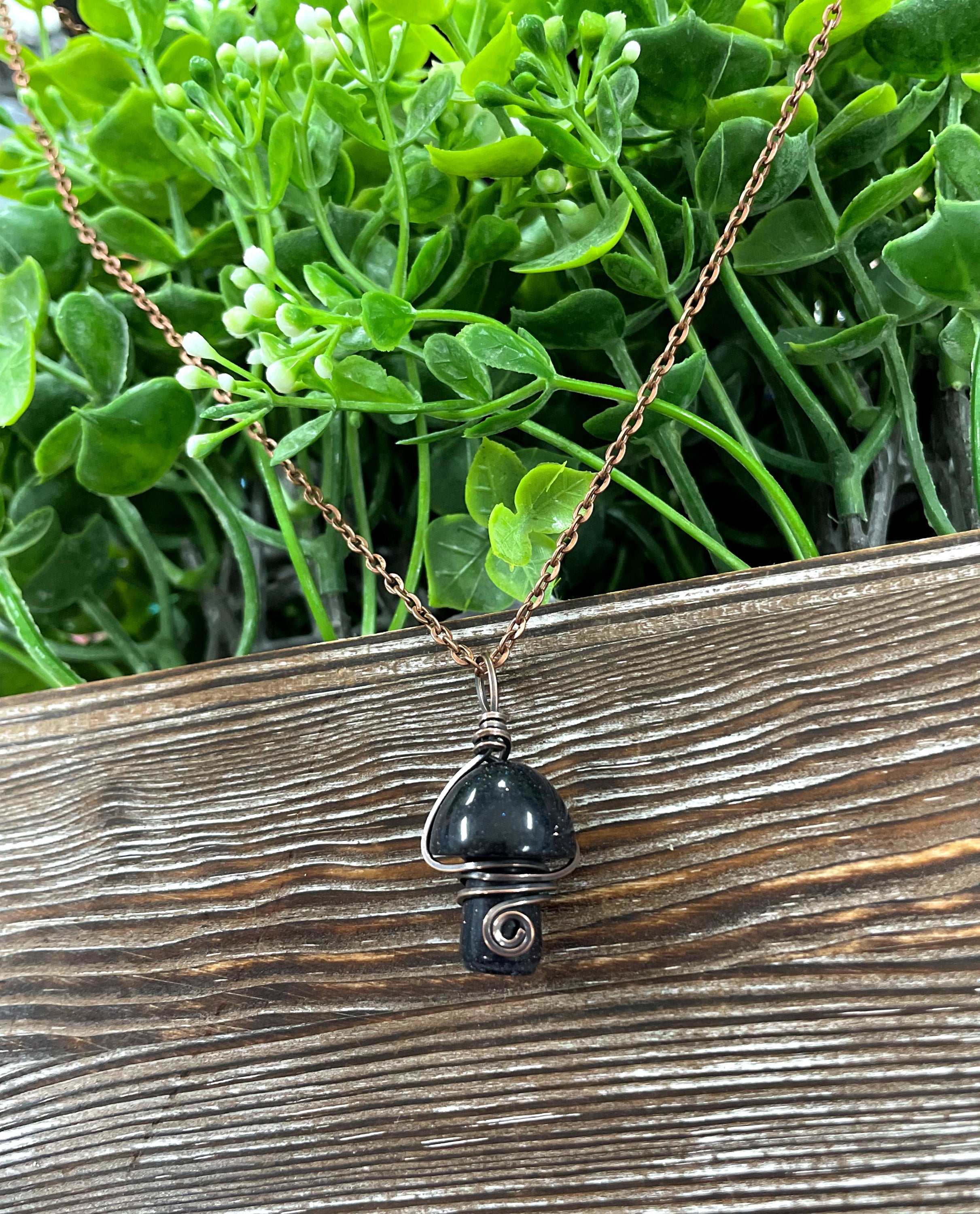 Wire Wrapped Mushroom Gemstone Pendant featuring a charming mushroom-shaped gemstone wrapped in oxidized copper wire on a 21-inch cord.