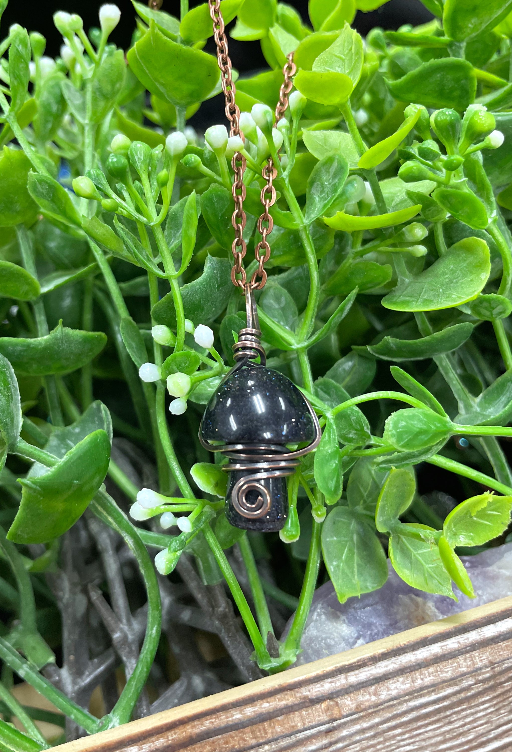 Wire Wrapped Mushroom Gemstone Pendant featuring a charming mushroom-shaped gemstone wrapped in oxidized copper wire on a 21-inch cord.