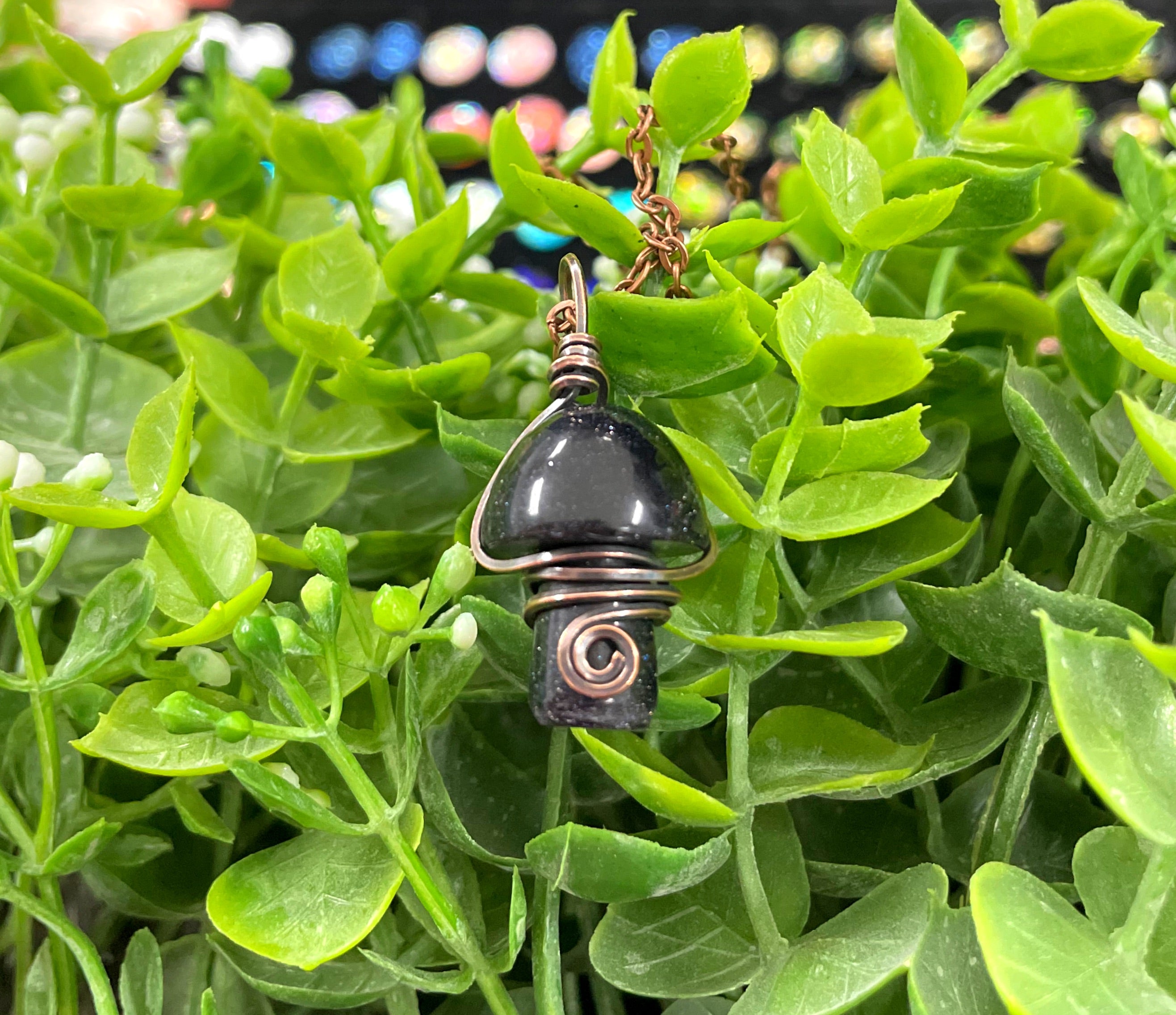 Wire Wrapped Mushroom Gemstone Pendant featuring a charming mushroom-shaped gemstone wrapped in oxidized copper wire on a 21-inch cord.